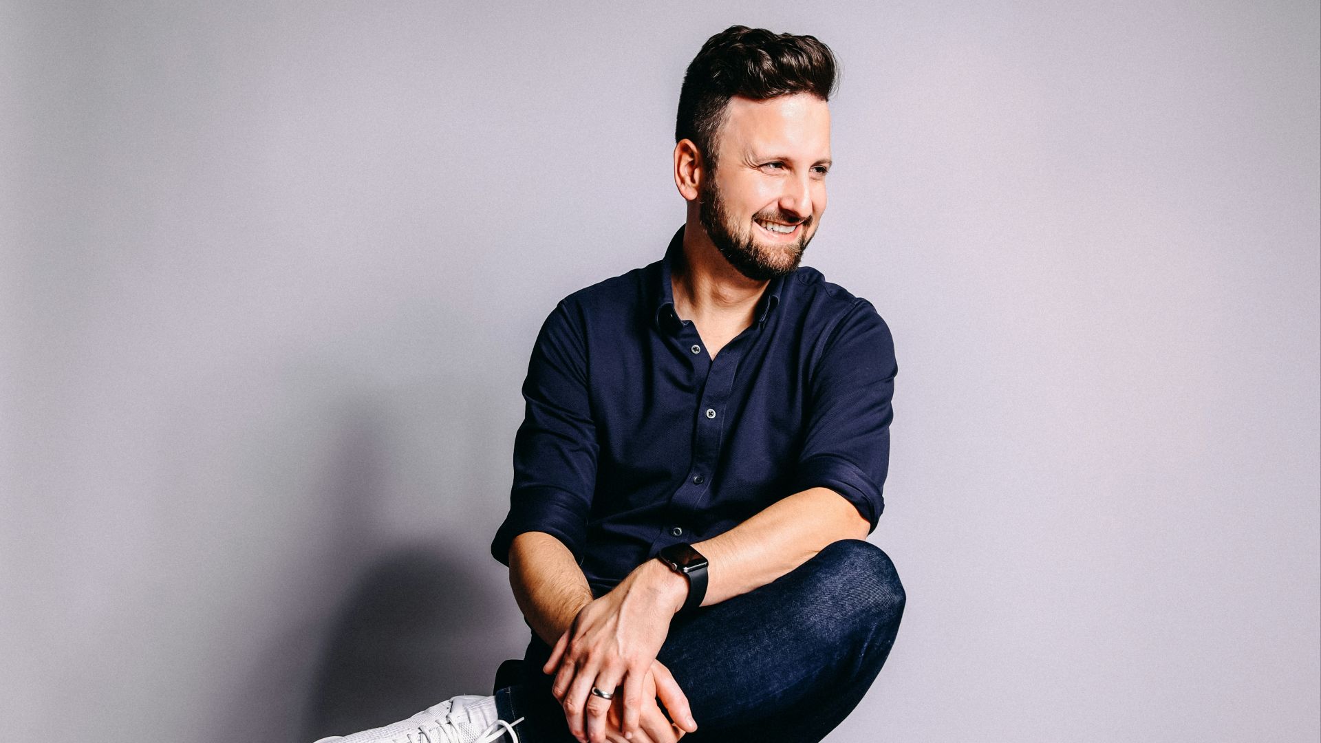 man in black dress shirt and blue denim jeans sitting on black chair