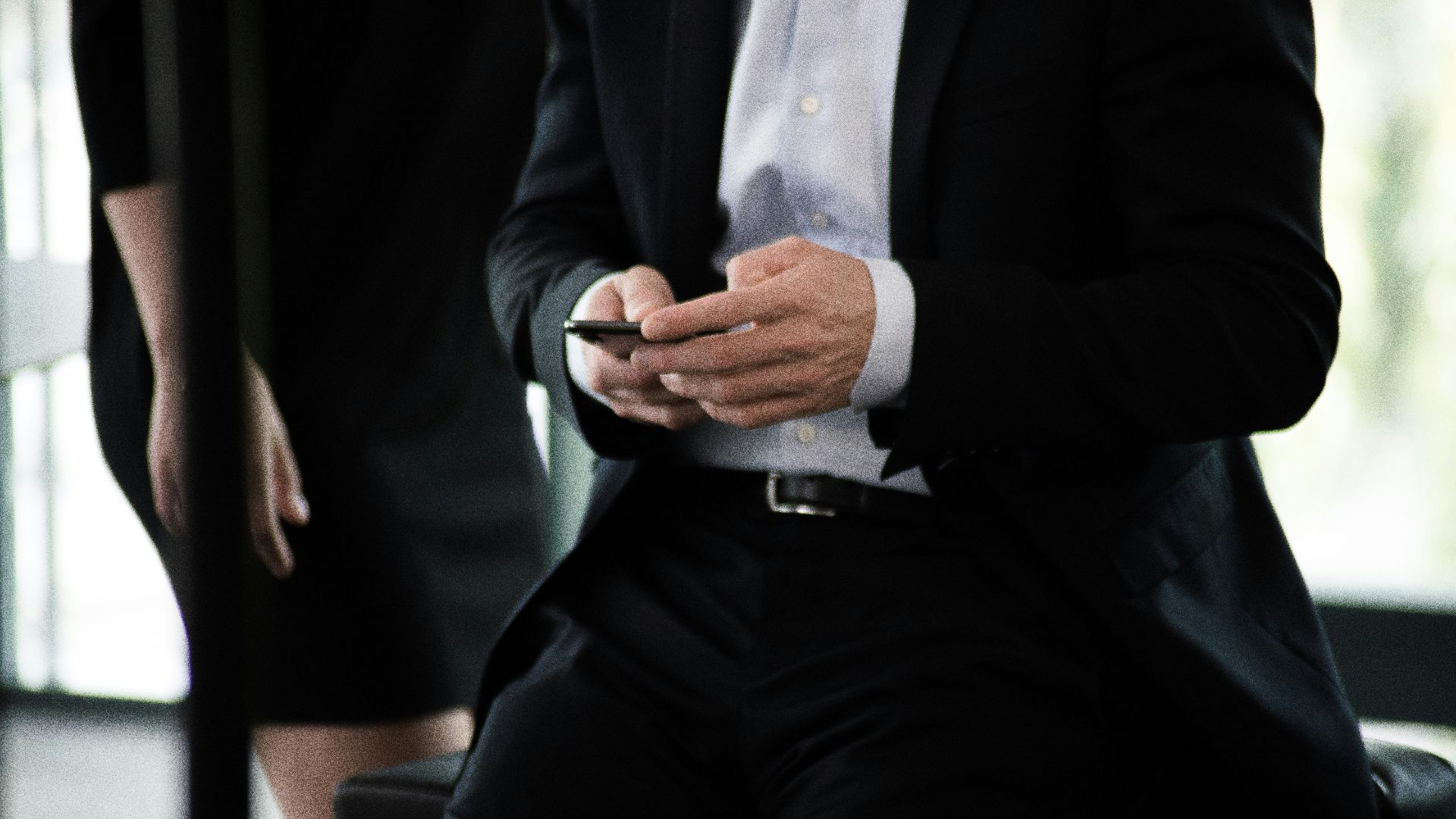 man in black suit with phone in hand