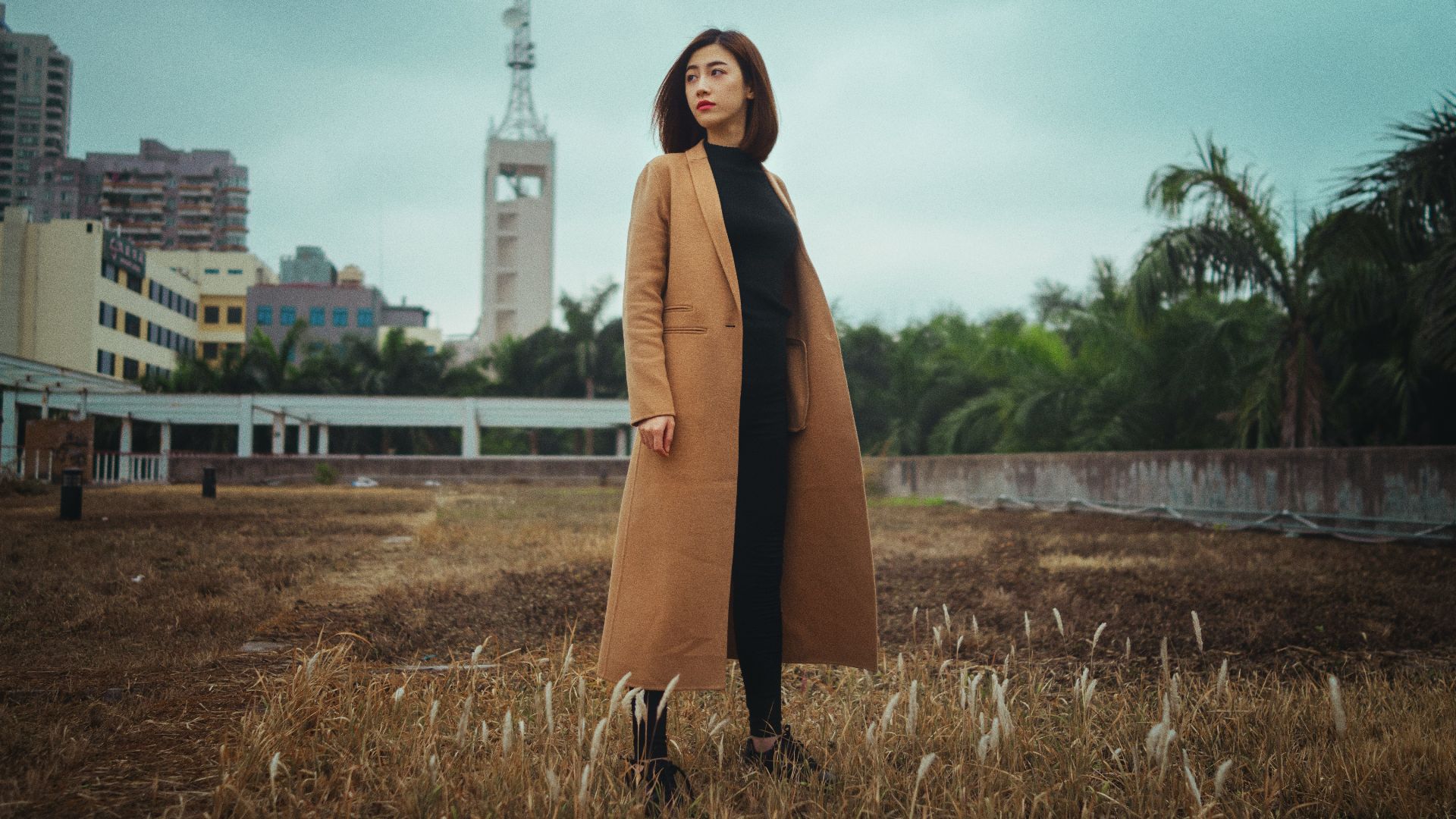 woman wearing brown coat standing on brown grass