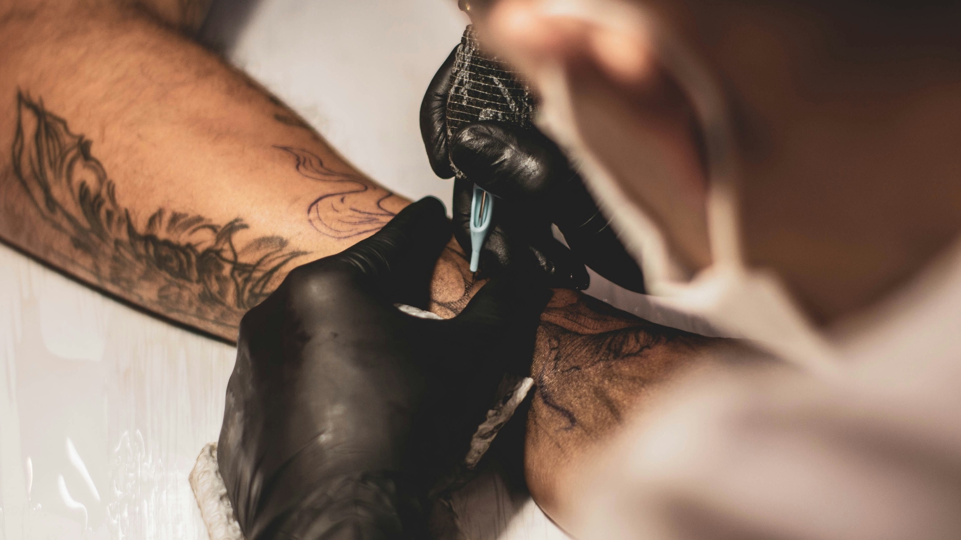 shallow focus photo of person tattooing person's right arm