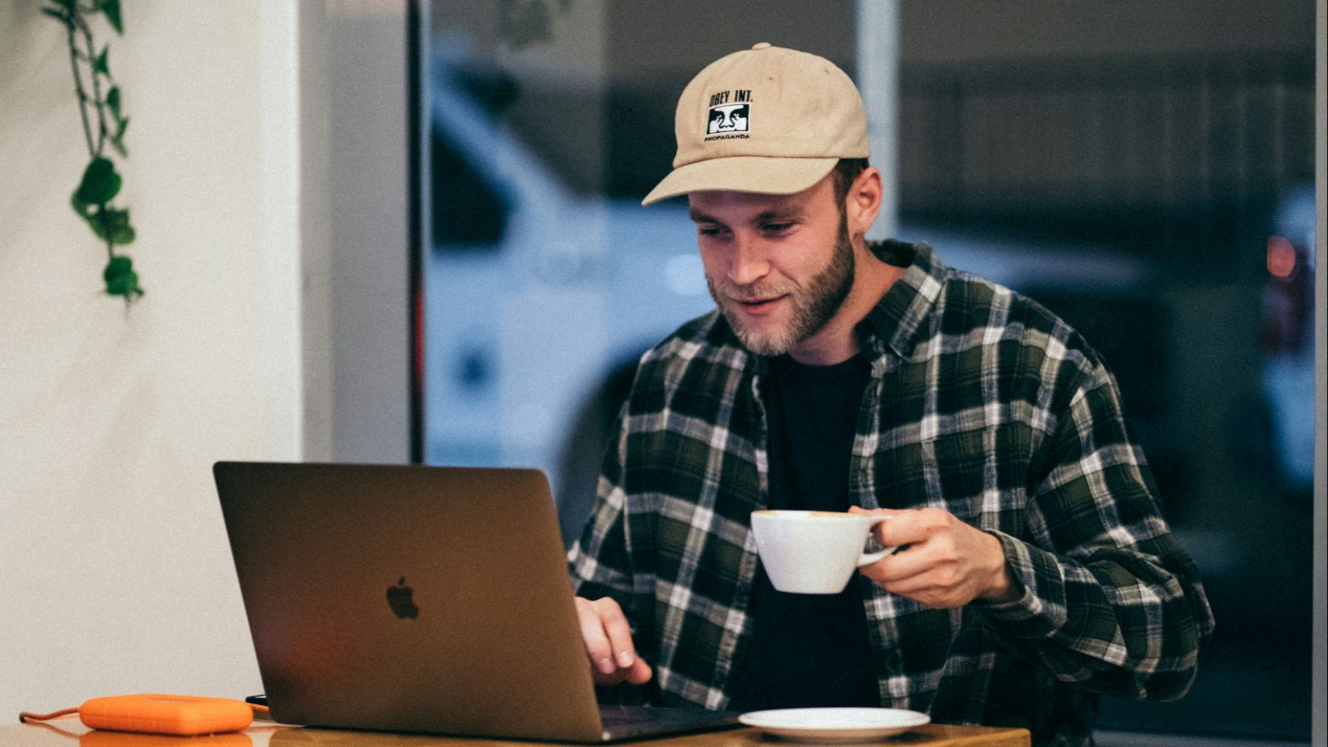 man sitting while having coffee and using laptop