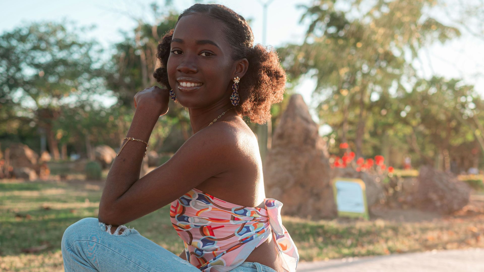 Young woman in jeans and heels crouching outdoors