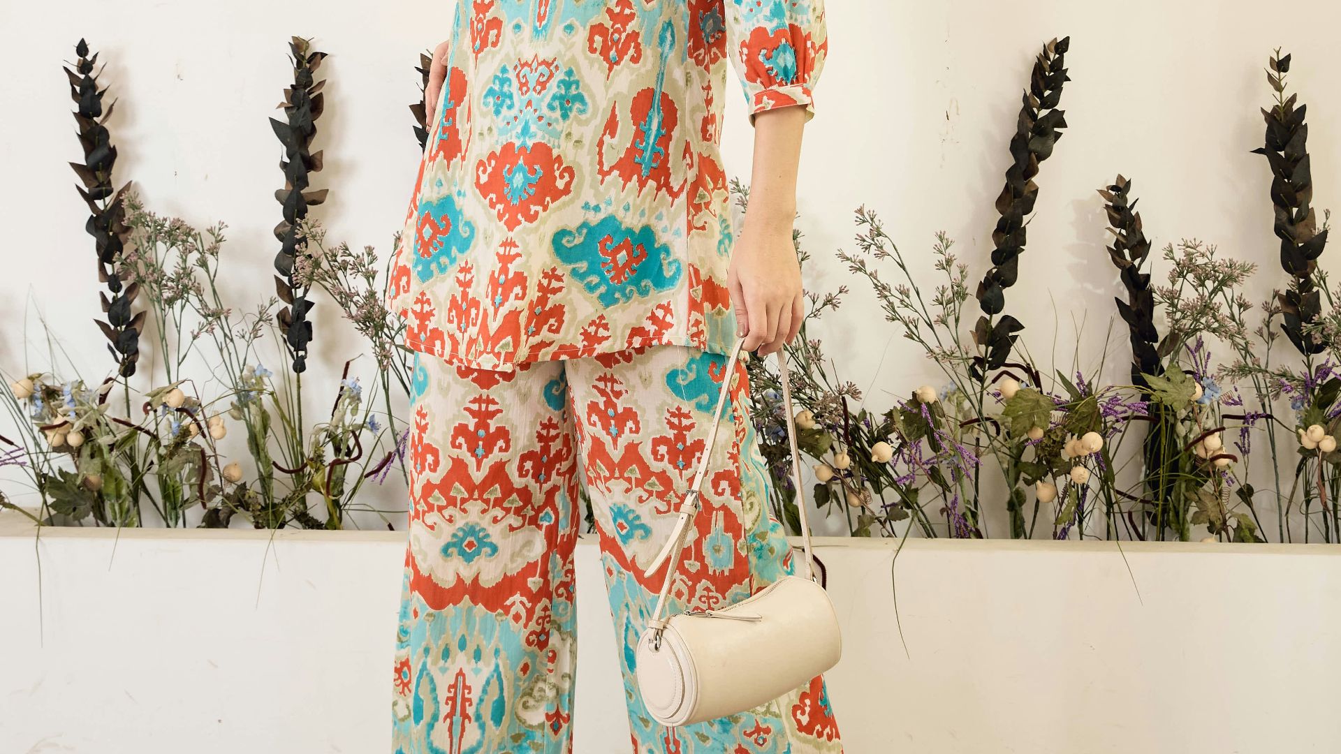 Woman in patterned clothing holding a small white purse