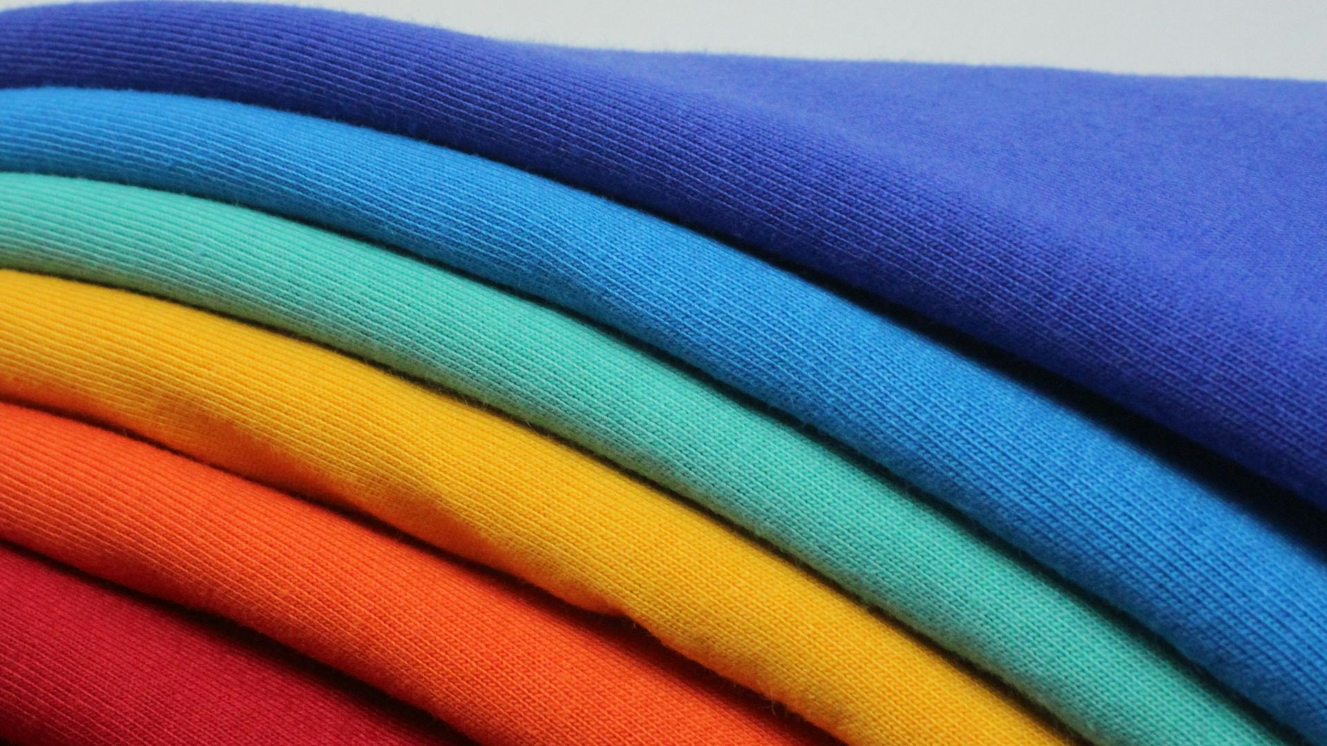 a stack of different colored t - shirts sitting on top of each other
