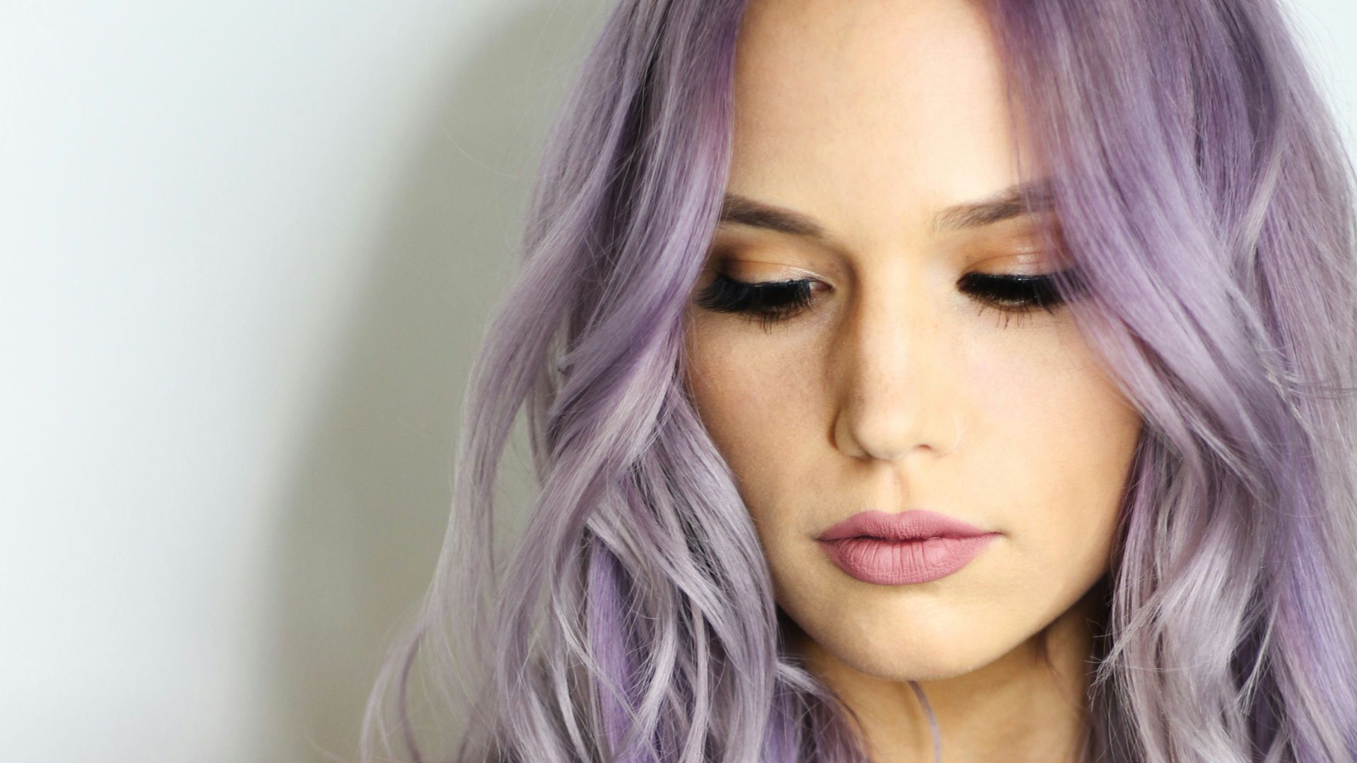 purple haired woman in black top leaning on wall