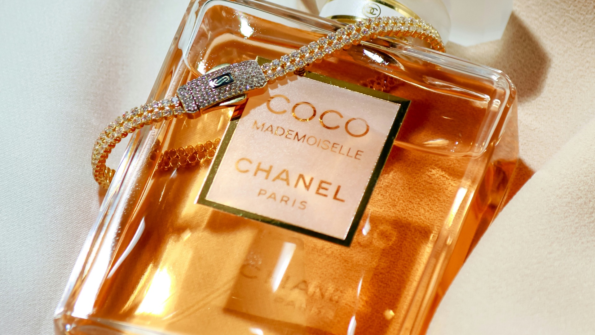 a bottle of perfume sitting on top of a bed