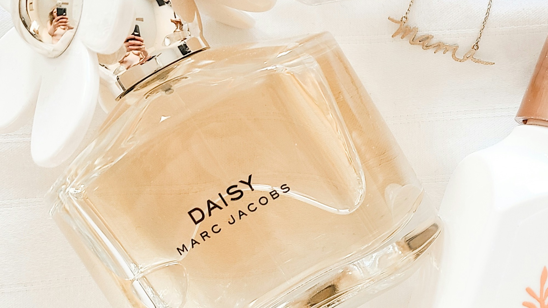 a bottle of perfume sitting next to a necklace