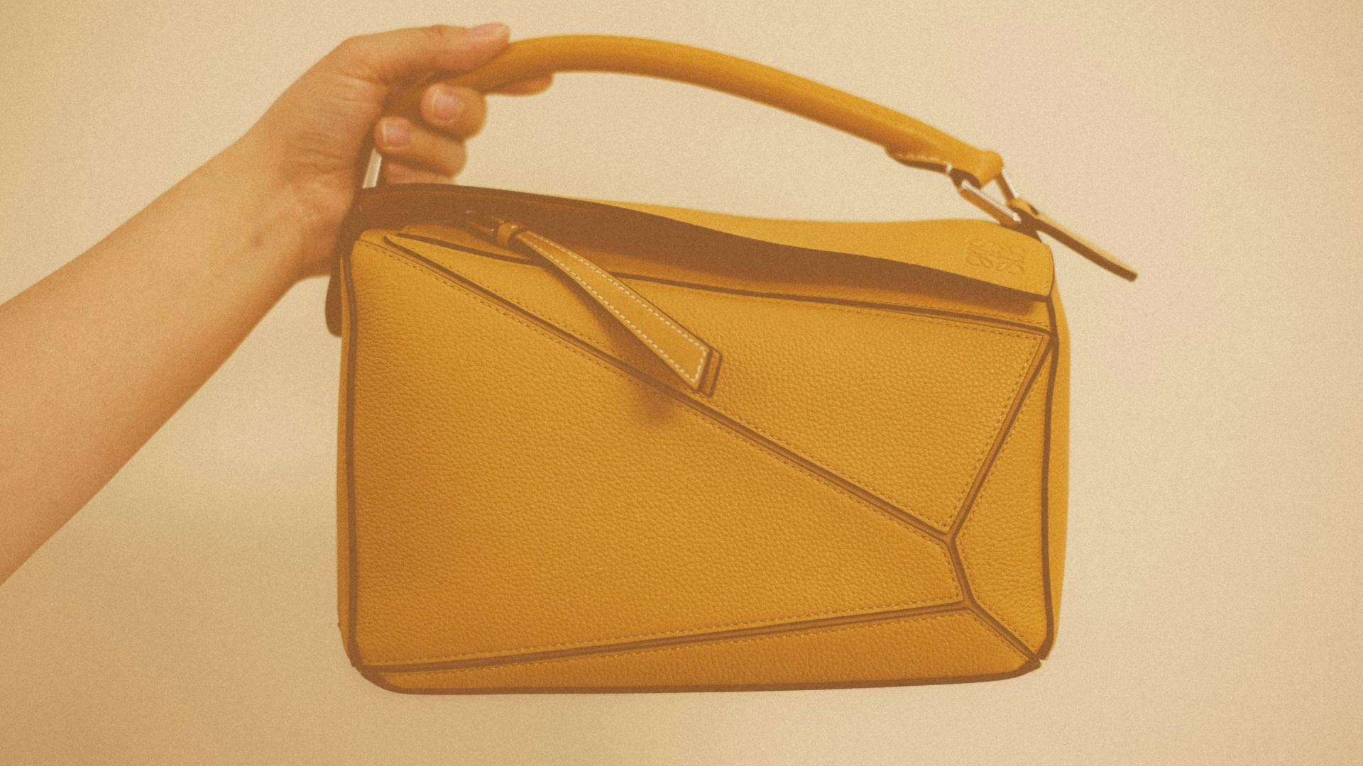 a hand holding a brown purse