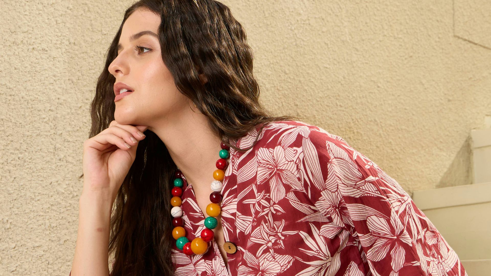 Woman in floral print clothing sitting on stairs.