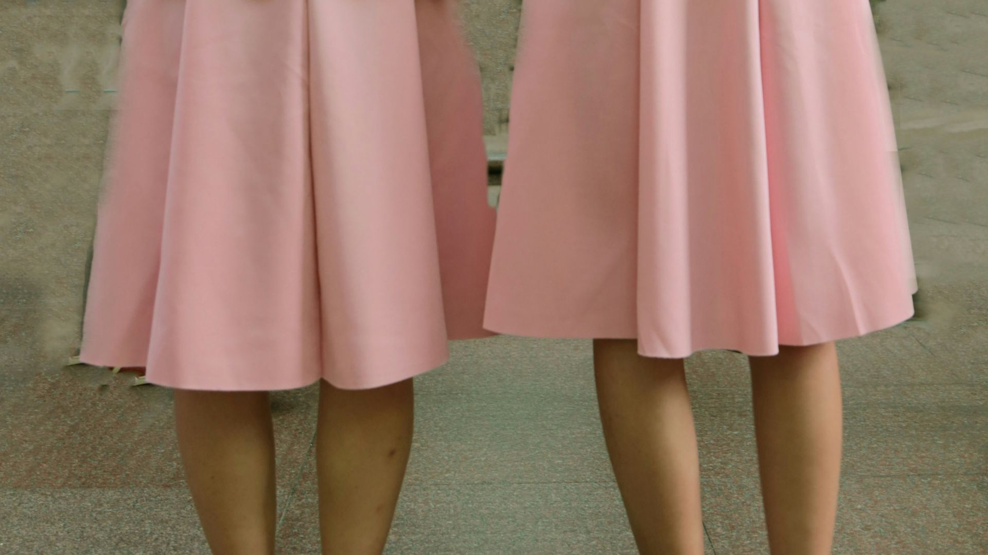 two women wearing pink skirts
