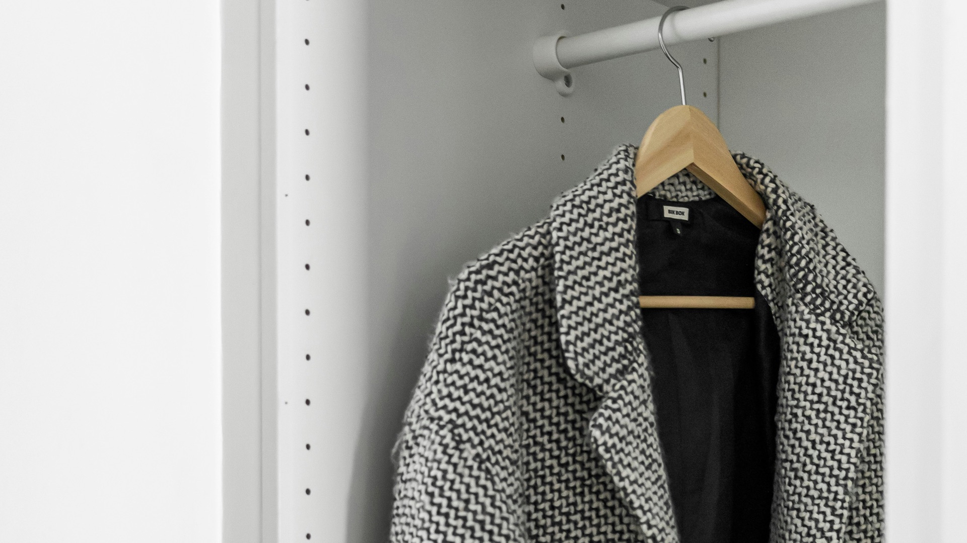 A coat hanging on a coat rack in a closet