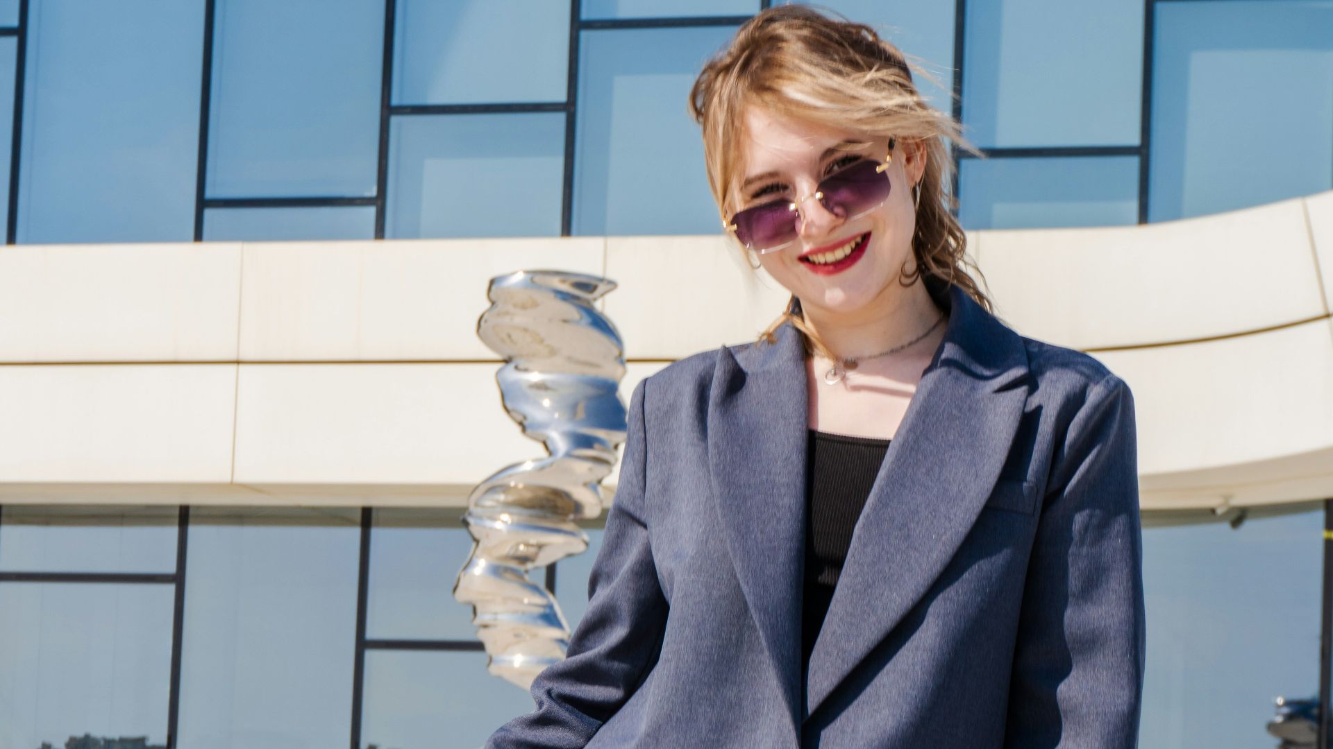 Young woman in blazer standing outside modern building