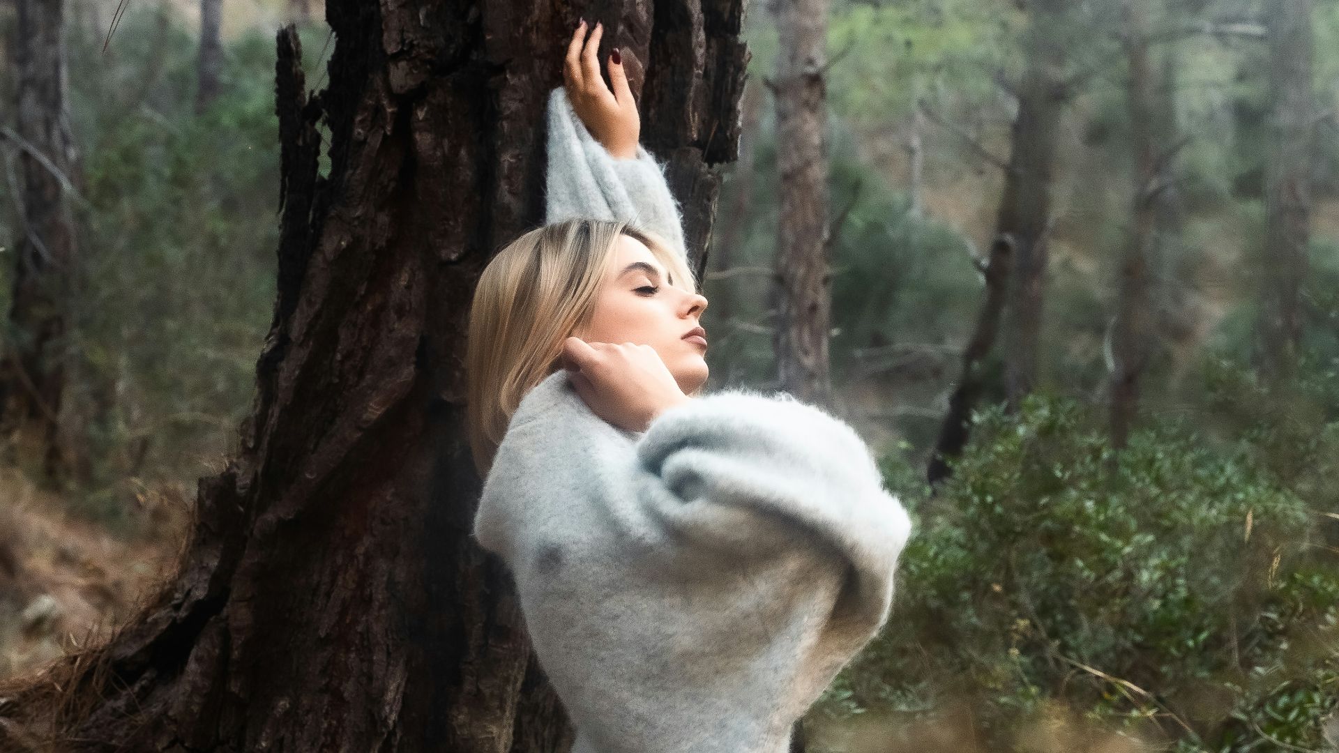 Woman in a sweater standing in a forest