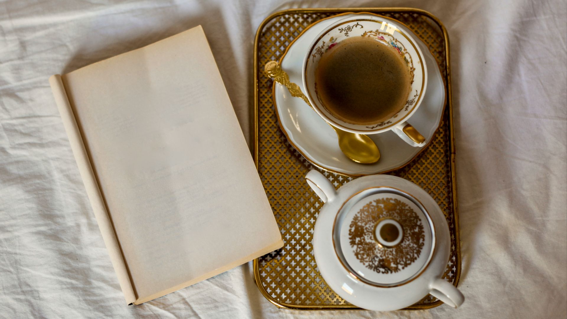 a cup of coffee and a book on a bed