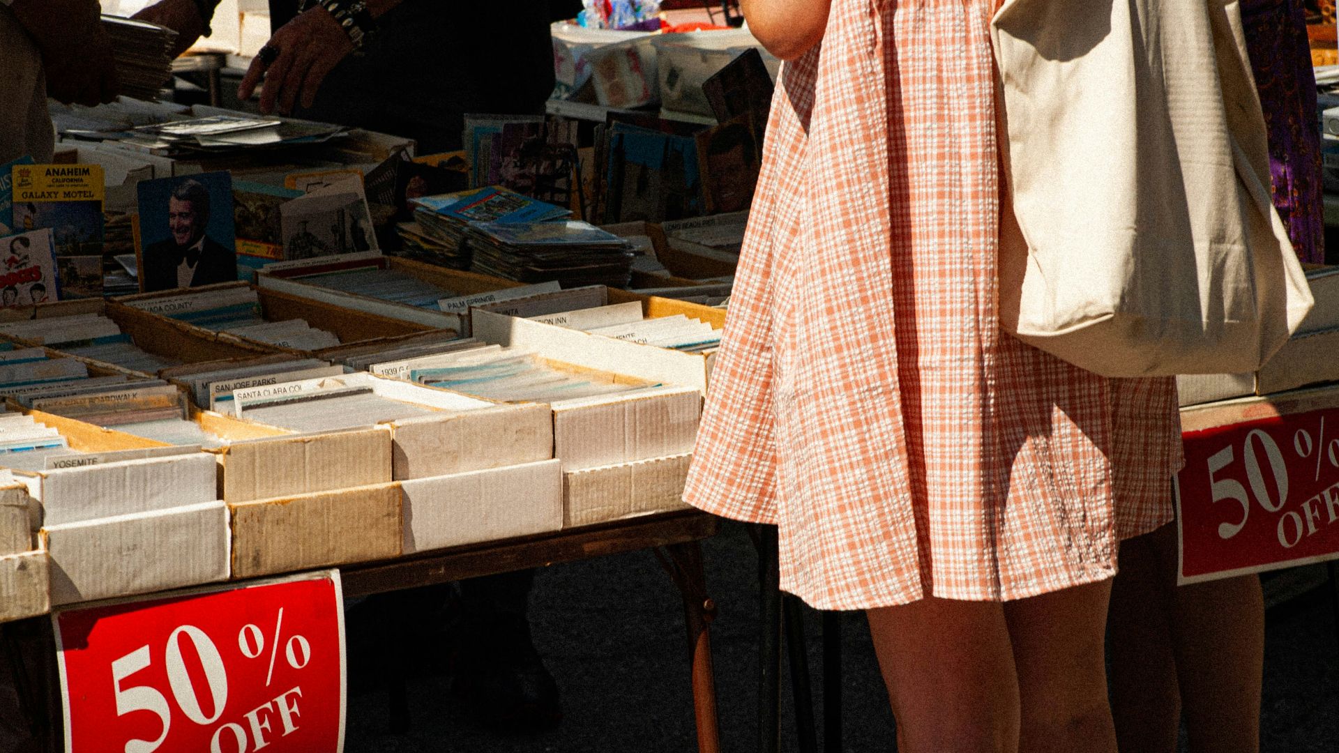 woman in white and red plaid dress standing beside brown wooden table