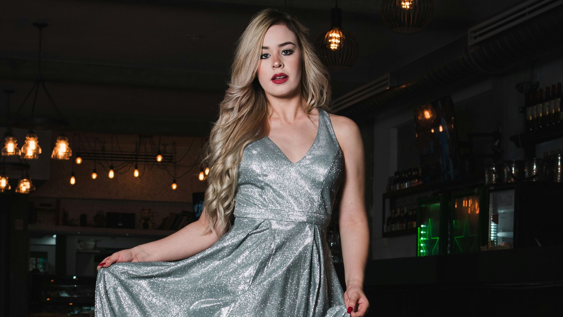 Woman in a shimmering silver dress walks indoors.
