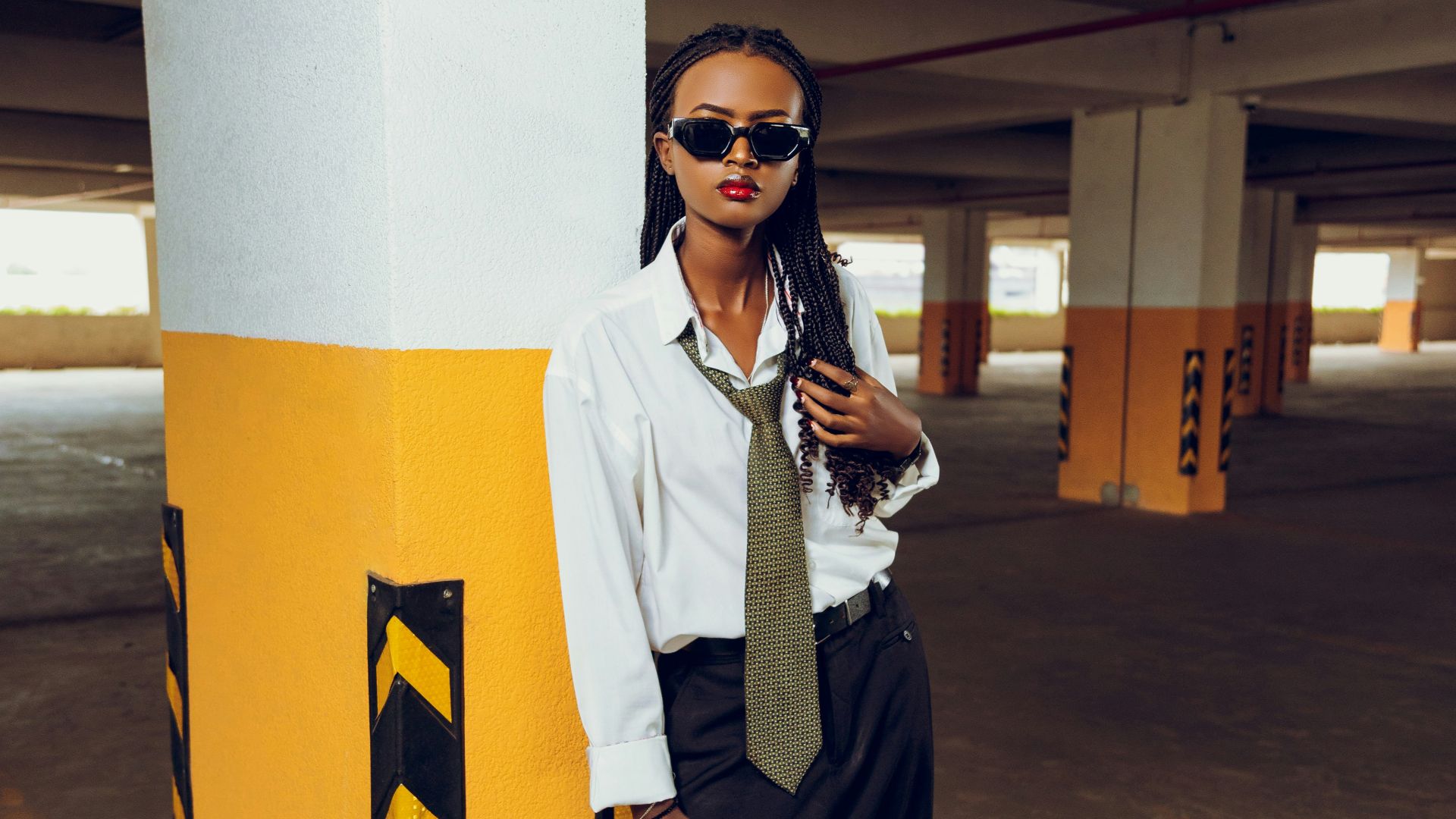 Woman in white shirt and tie in parking garage.