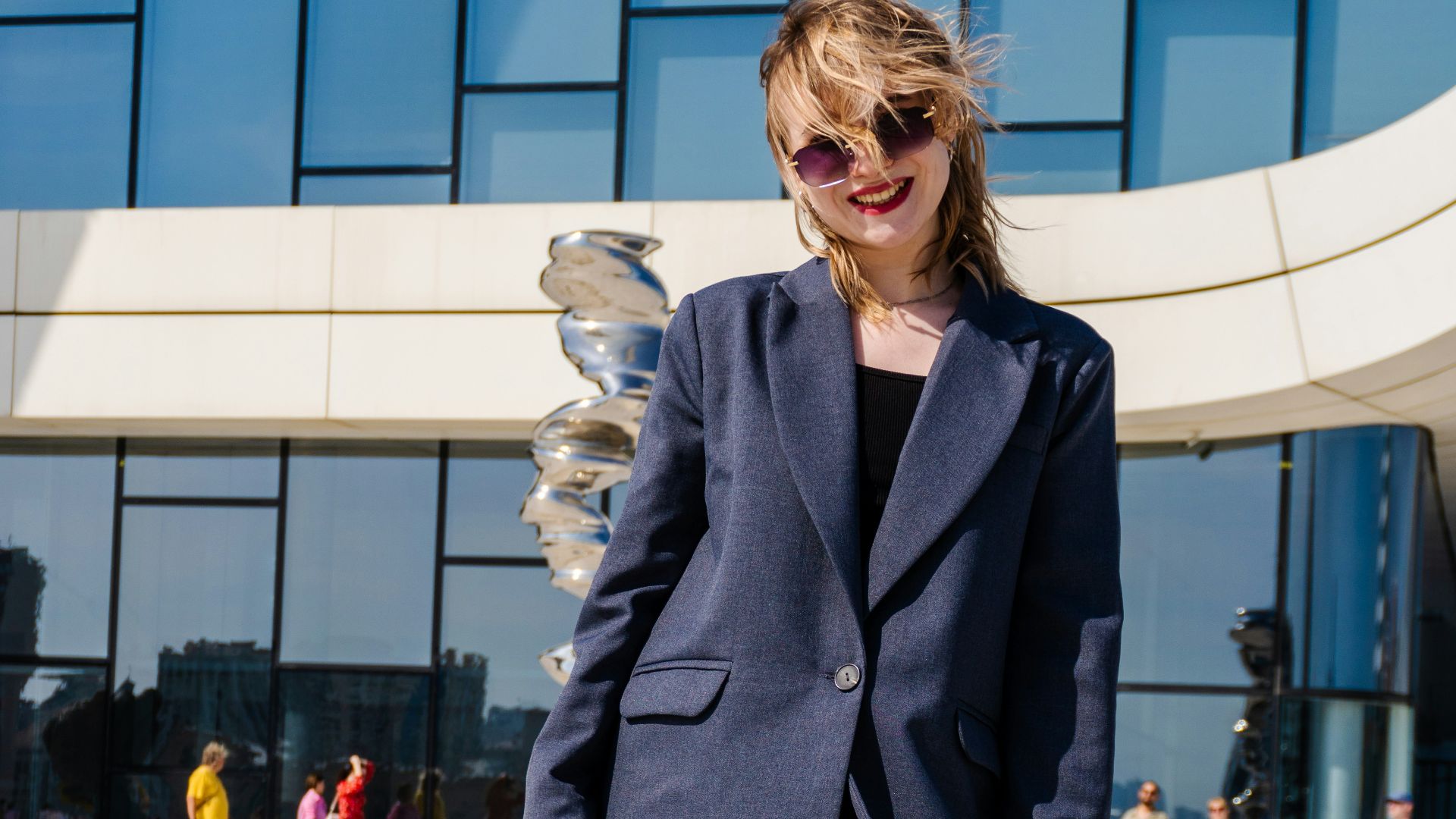 Woman in blazer and sunglasses outside modern building