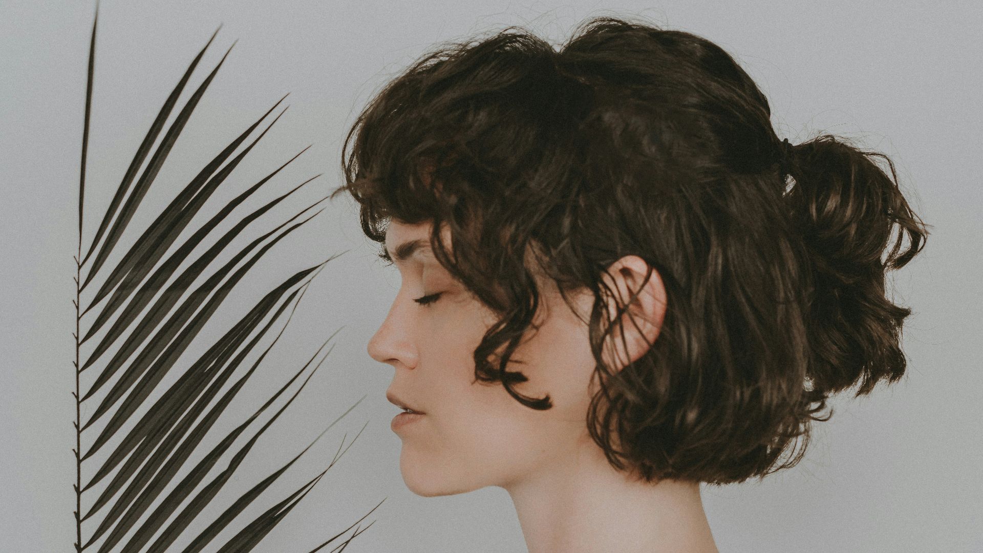 a woman standing in front of a palm leaf