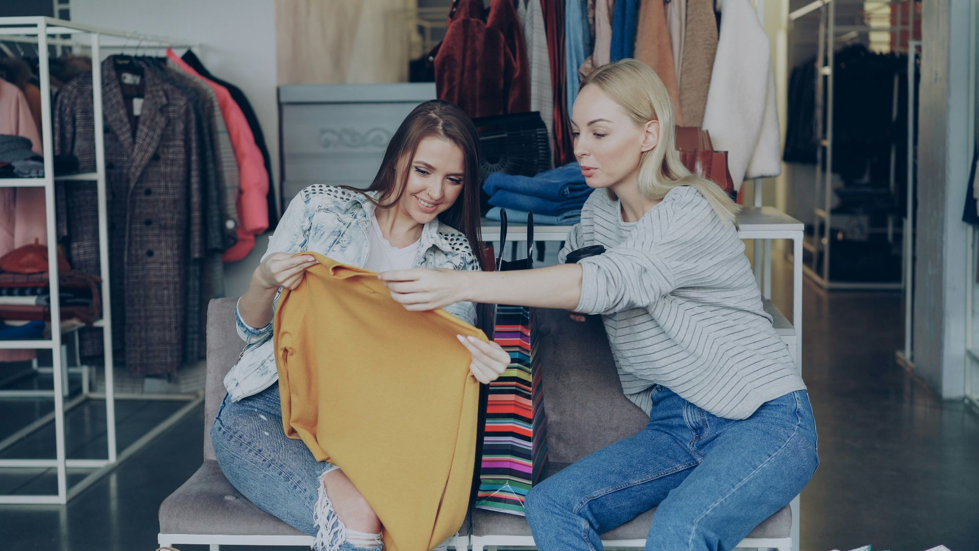 Two women discuss a sweater in a clothing store.