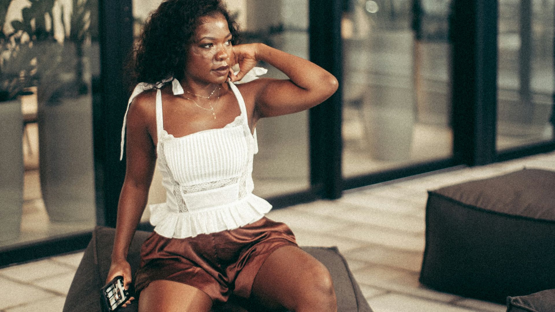 Woman relaxes on a beanbag outdoors, looking thoughtful.