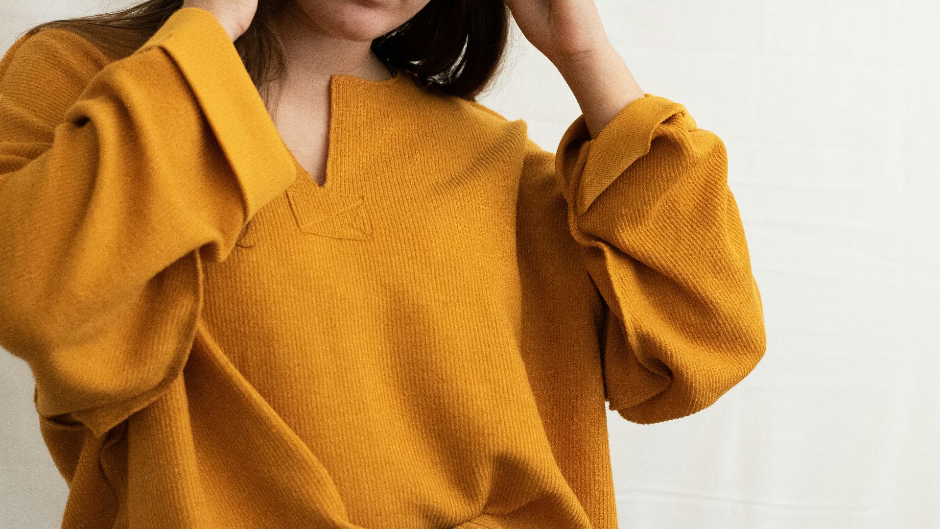 a woman in a yellow sweater is holding her head