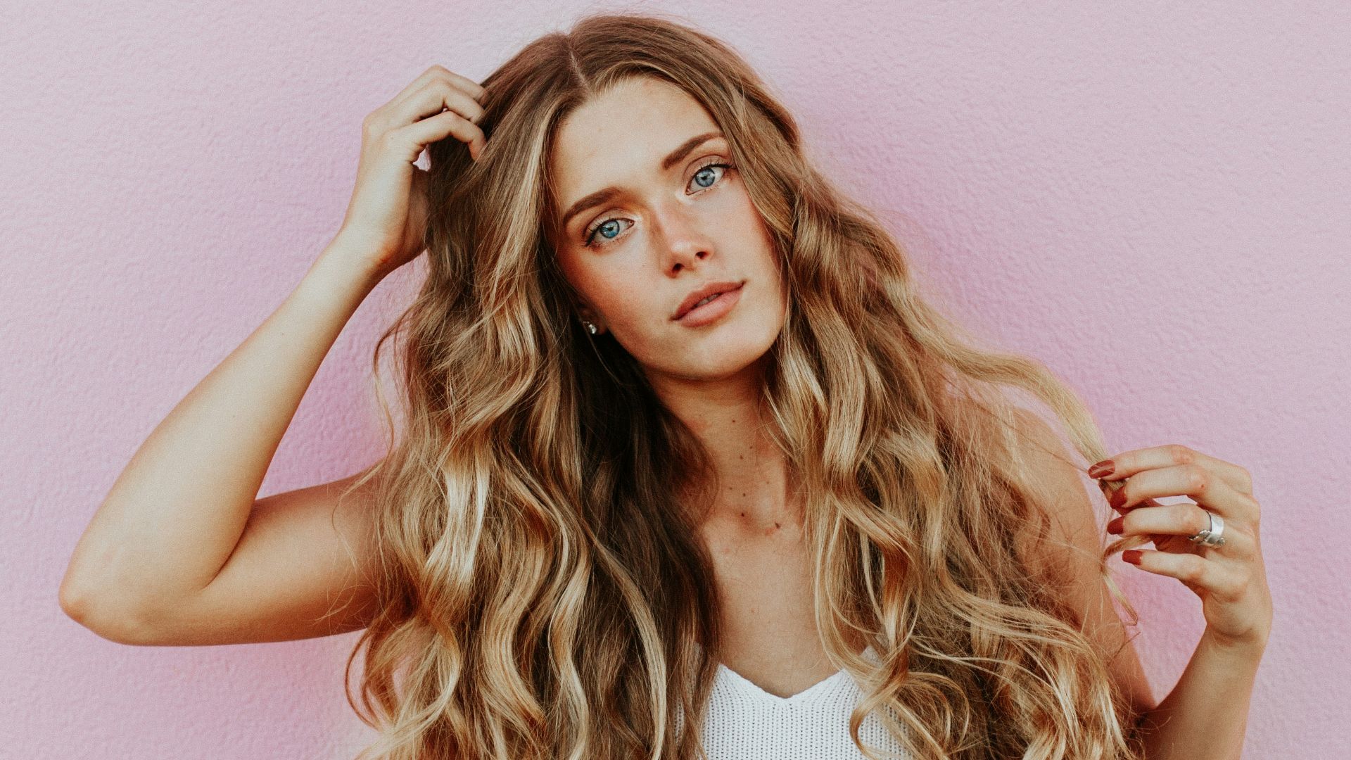 woman standing next to pink wall while scratching her head