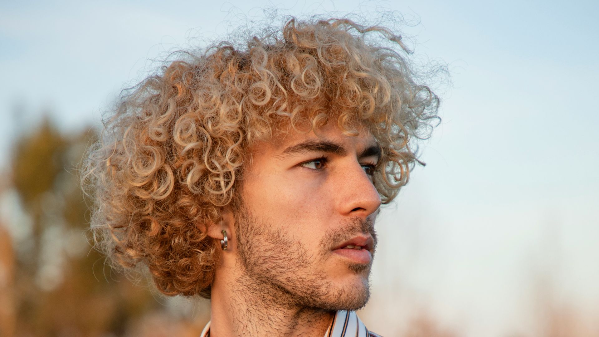 a man with curly hair wearing a striped shirt
