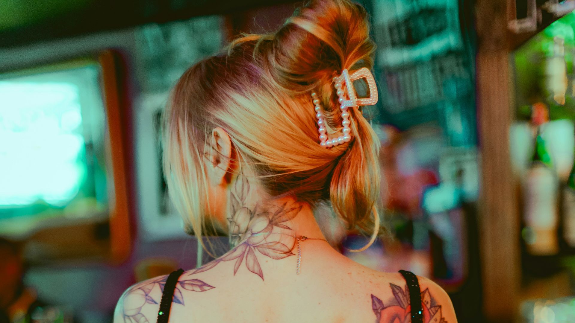 A woman sitting at a bar with a tattoo on her back