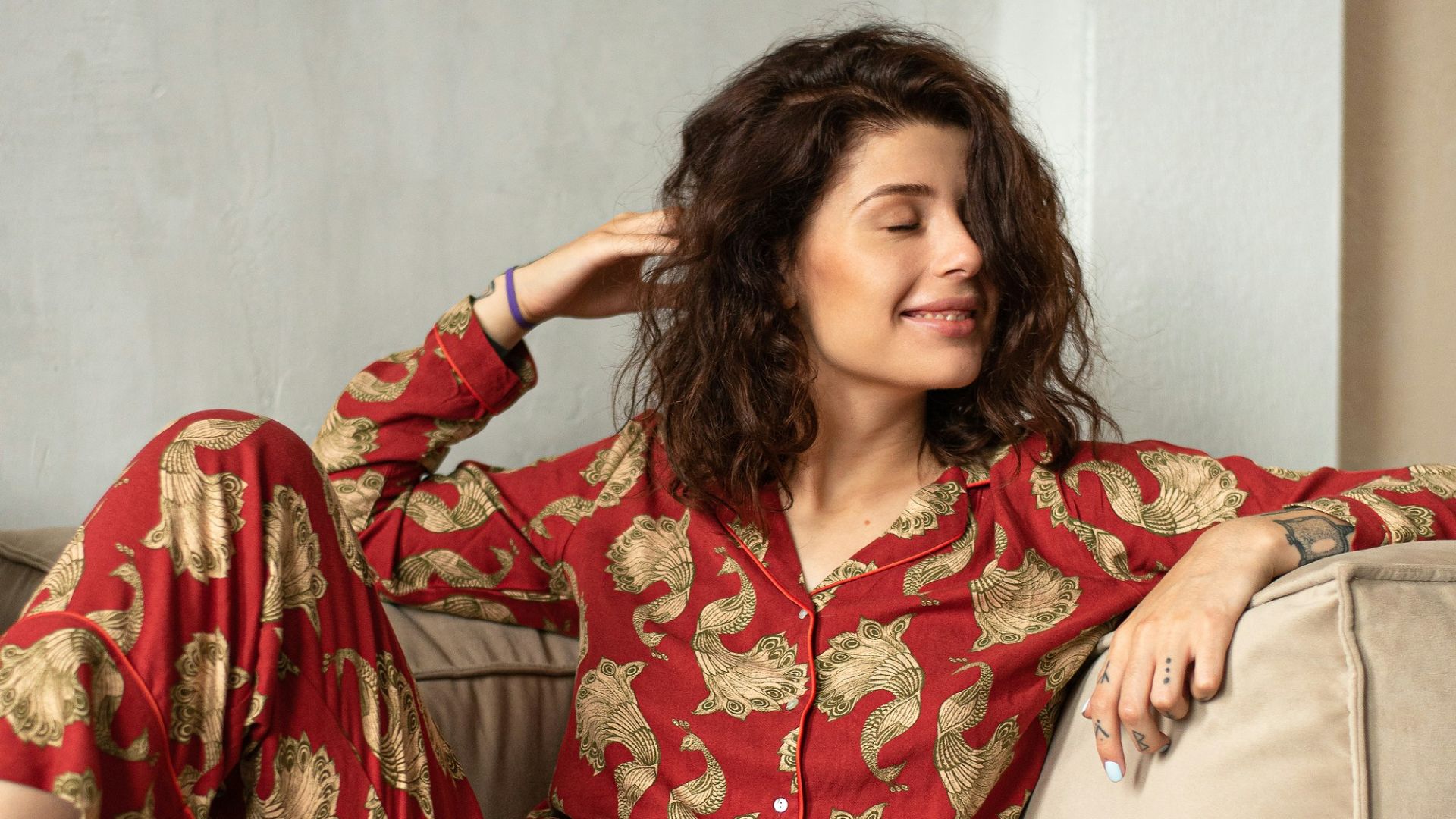 a woman sitting on a couch wearing a red and gold pajamas