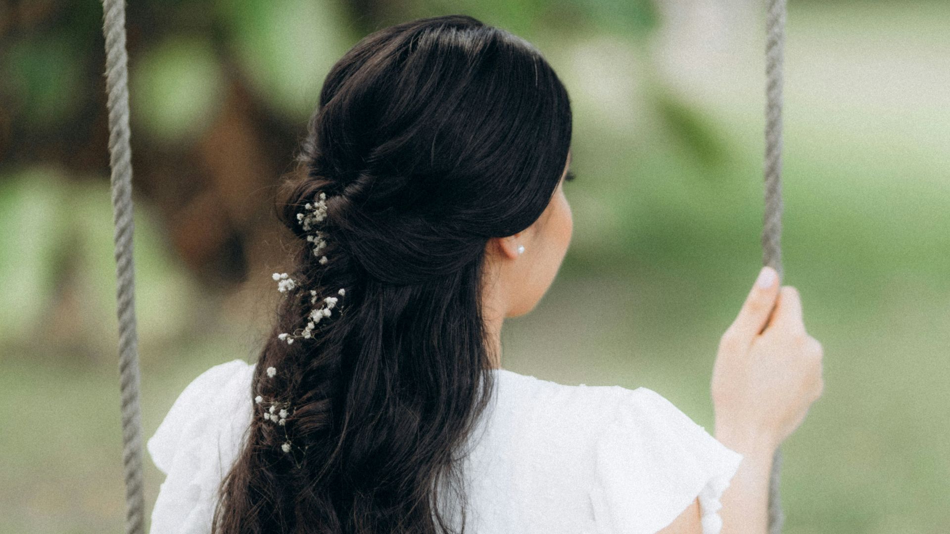 a woman in a white dress sitting on a swing