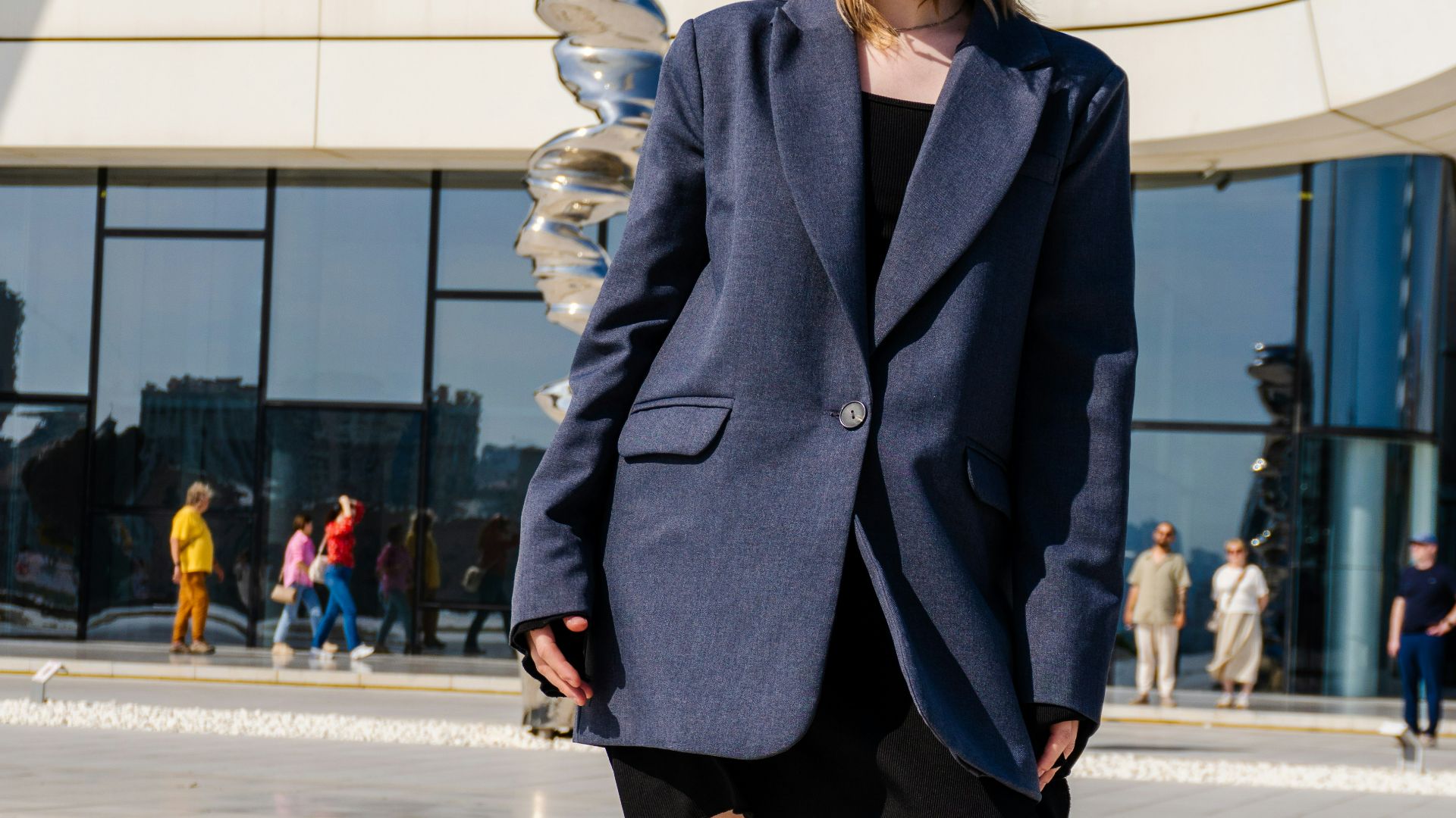 Woman in blazer and sunglasses outside modern building