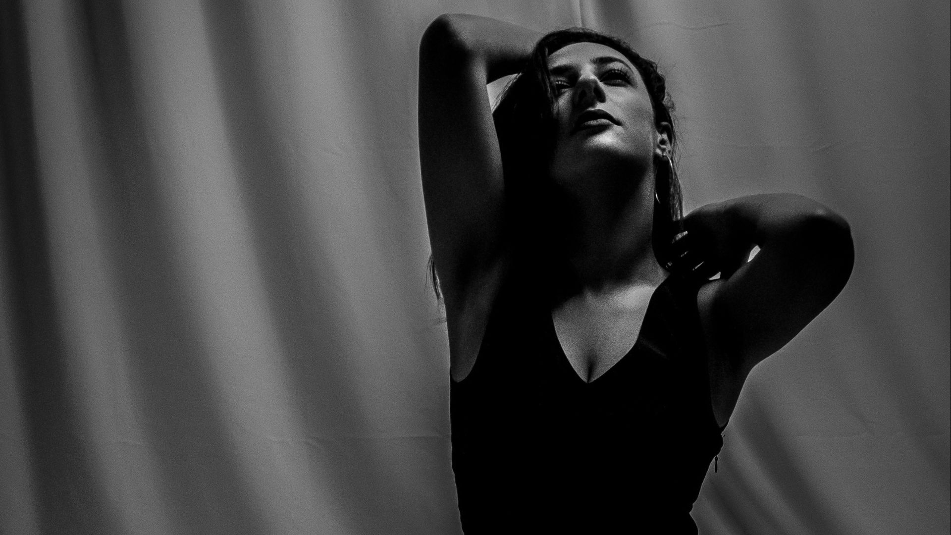 a woman in a black dress sitting on a bed