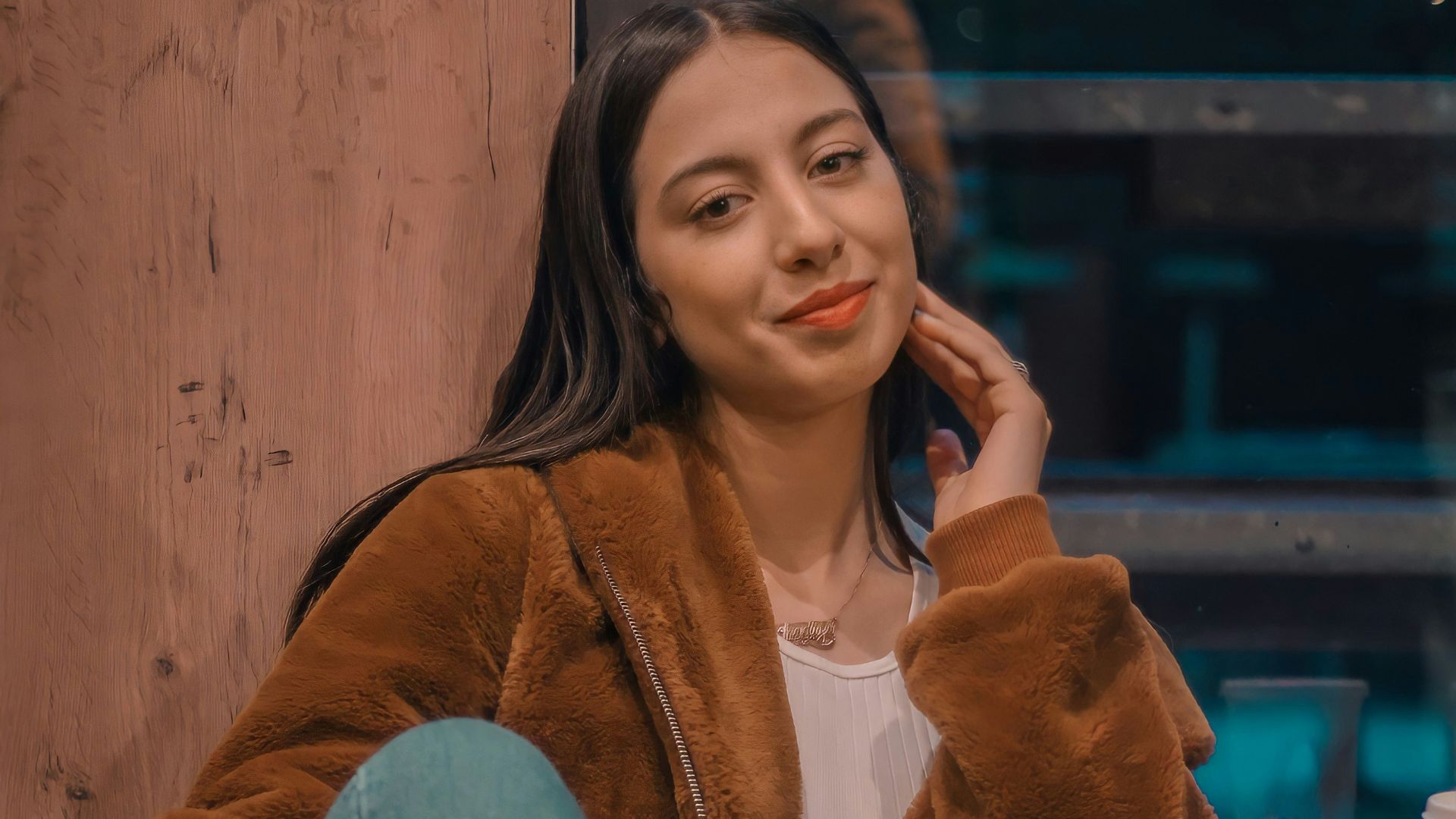 woman in brown fur coat and blue denim jeans sitting on chair