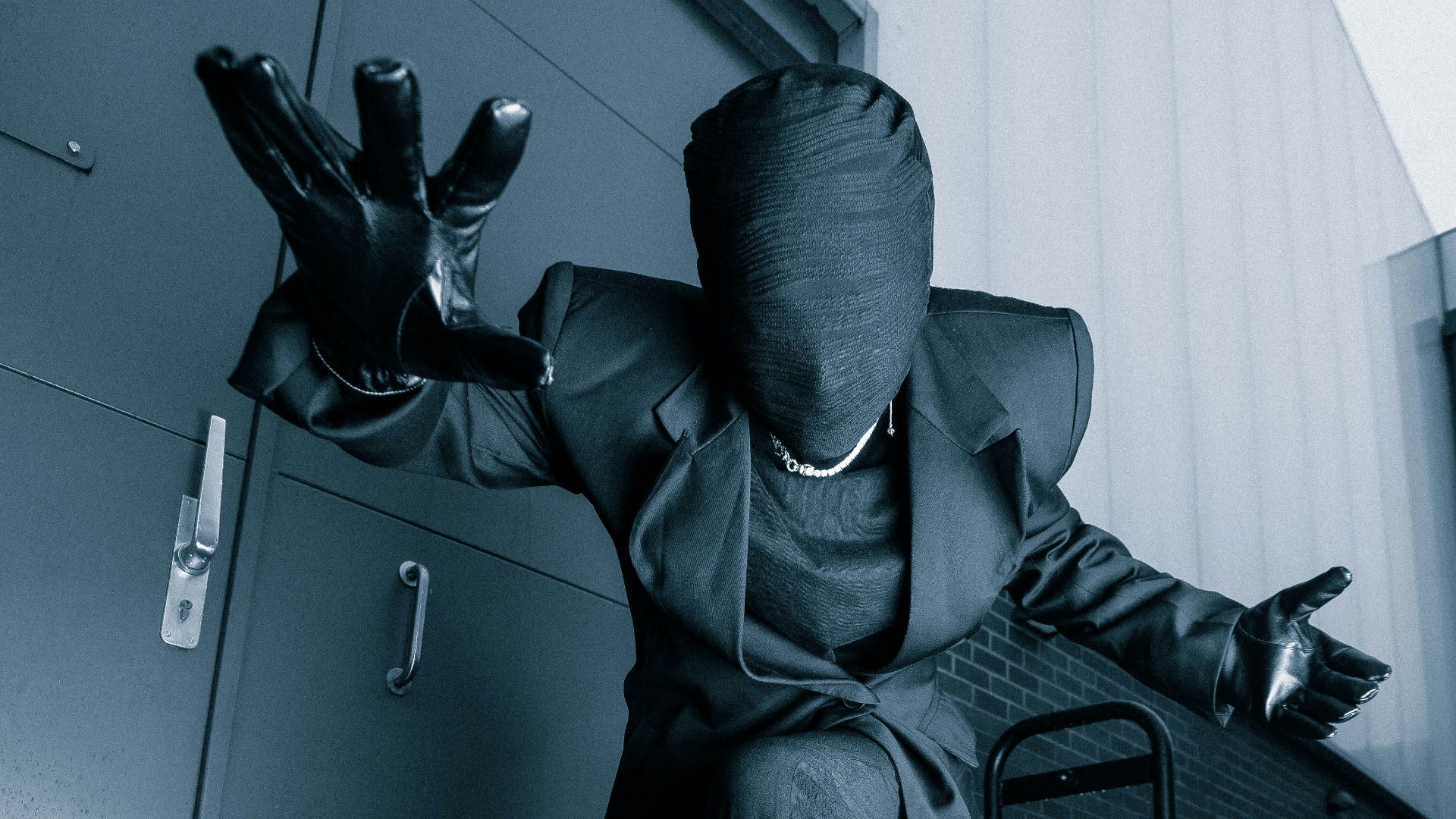 a man in a suit and rubber boots sitting on a chair