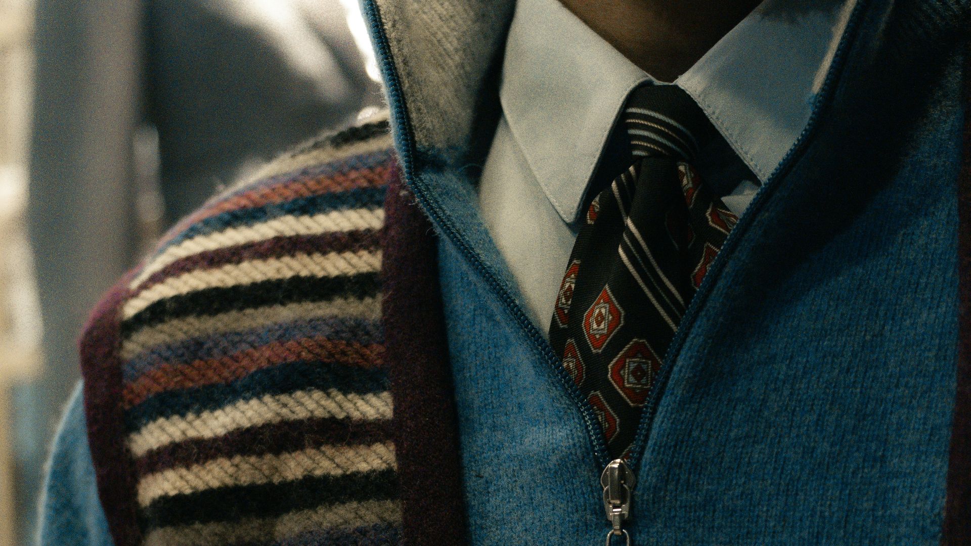 Man wearing a blue quarter-zip sweater over a collared shirt.