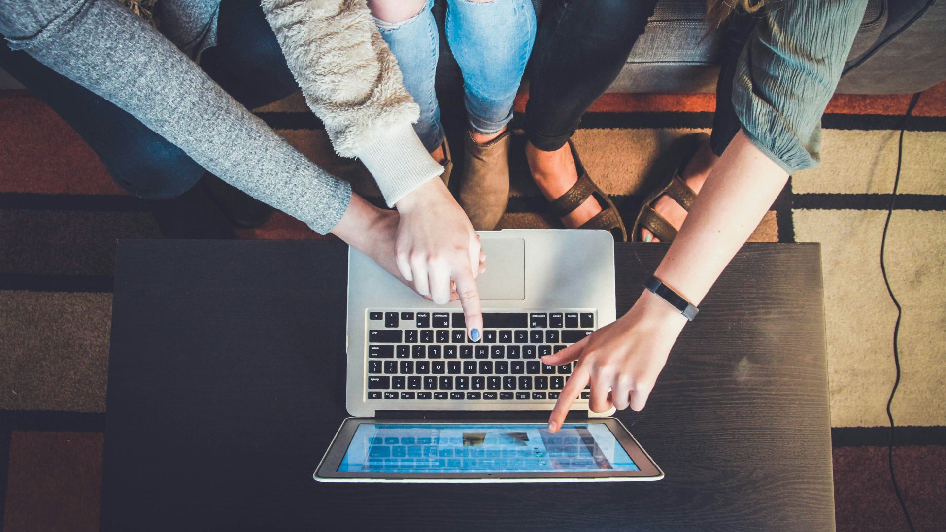 three person pointing the silver laptop computer