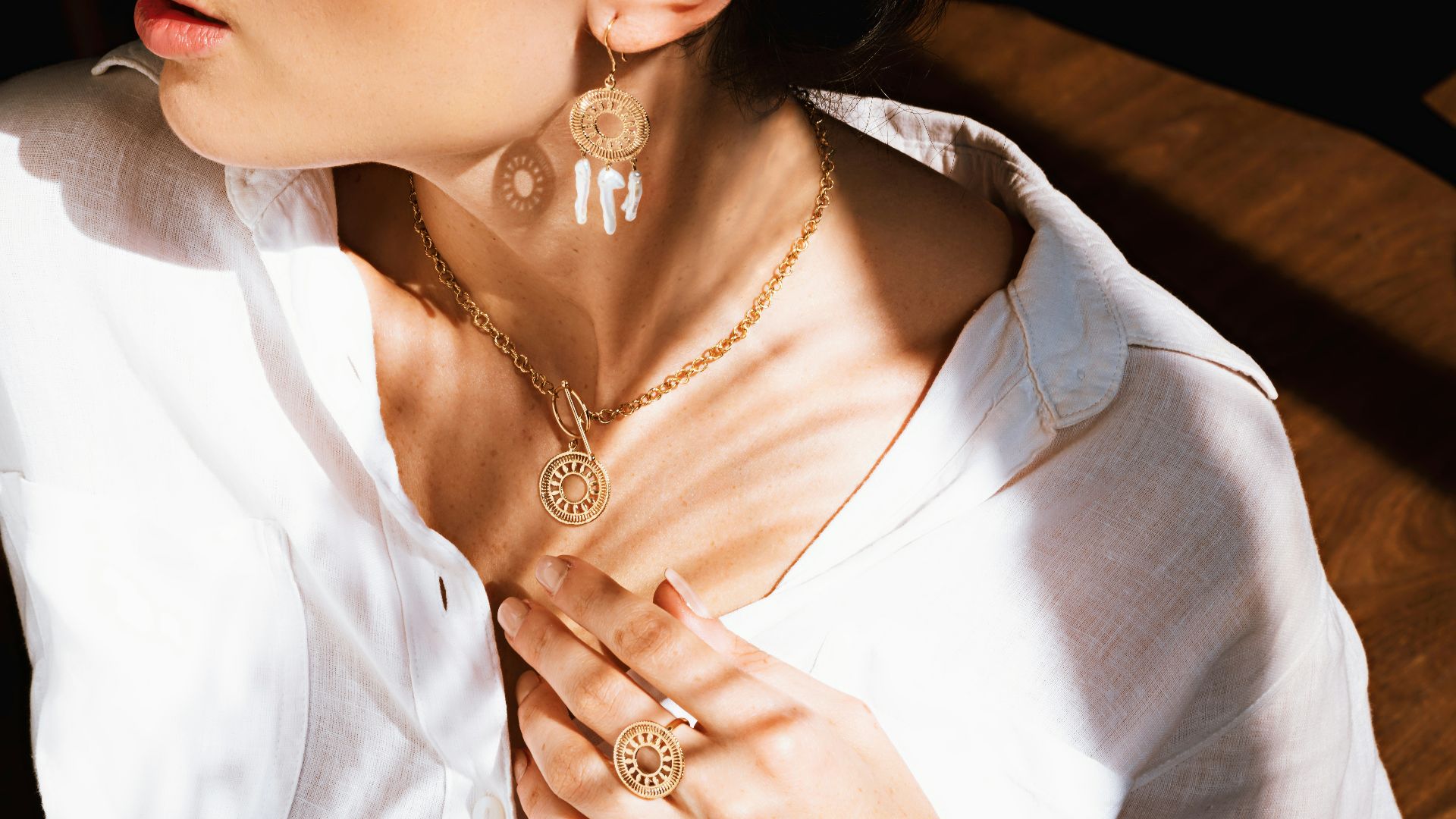 woman in white v neck shirt wearing gold necklace