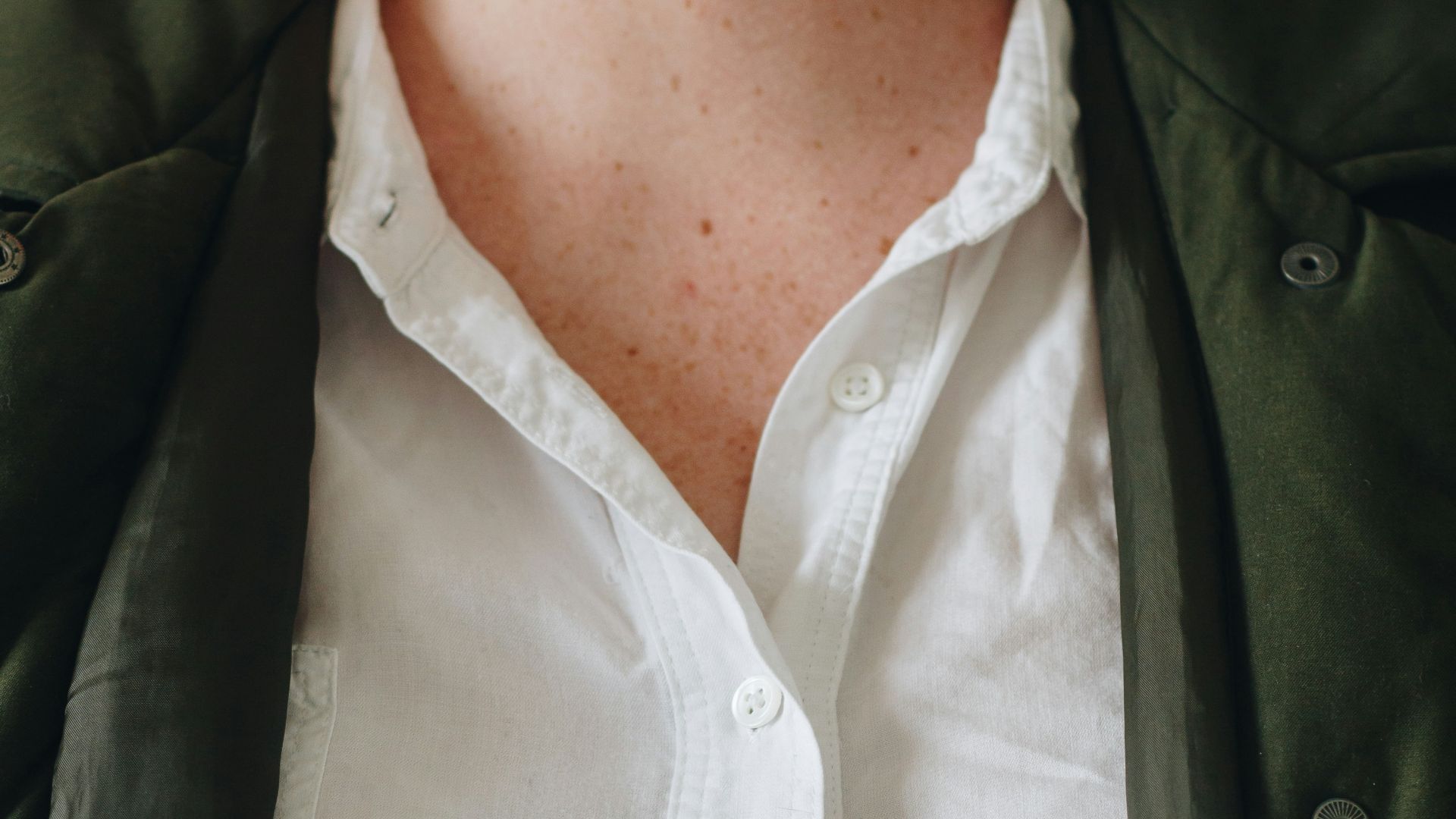 person in white button up shirt and green coat