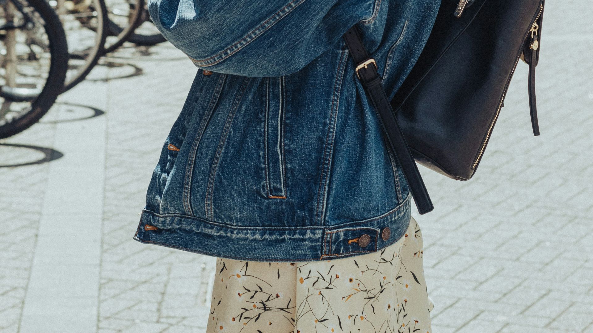 woman in blue denim jacket and blue denim jacket standing on sidewalk during daytime