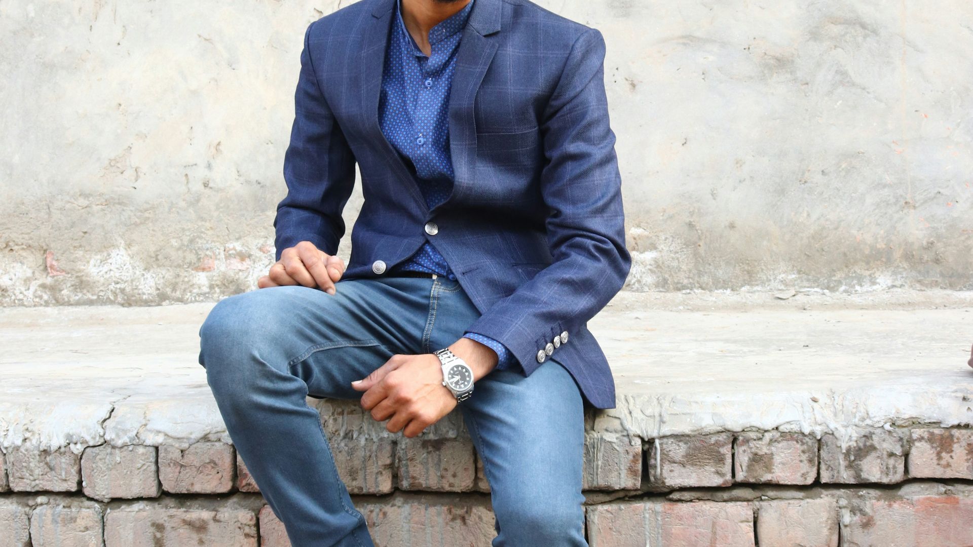 a man is sitting on a brick wall