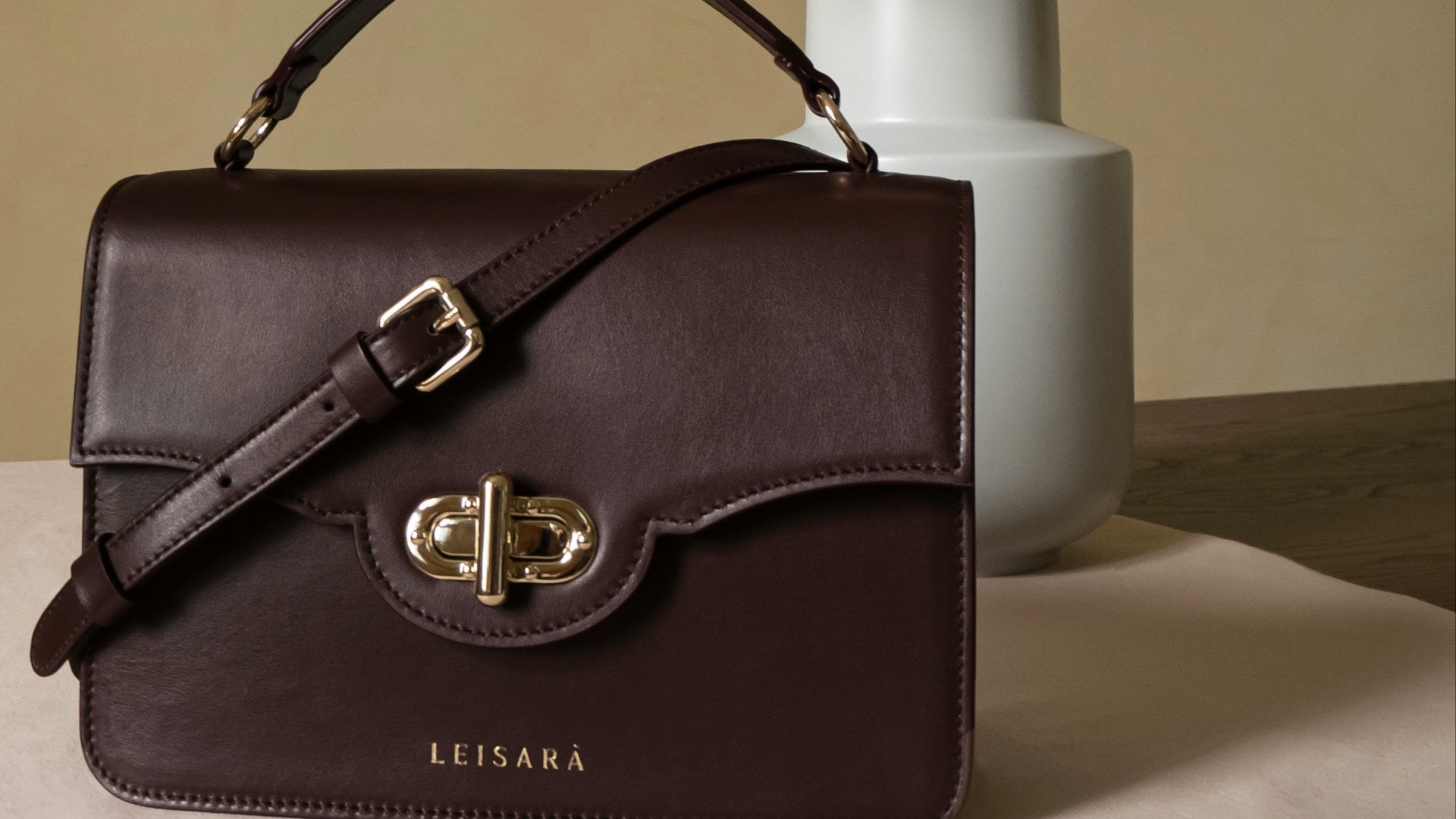 brown leather handbag beside white flower vase