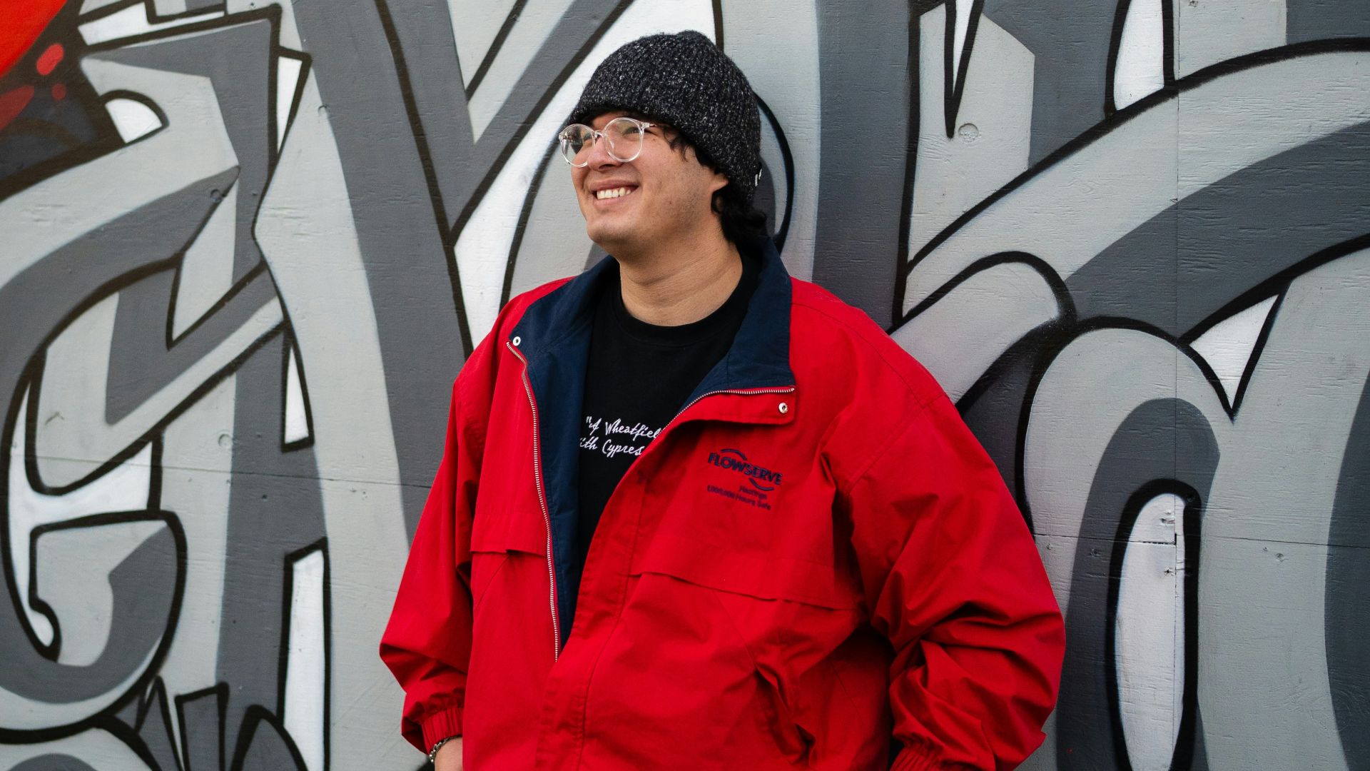 Man smiles by graffiti art.