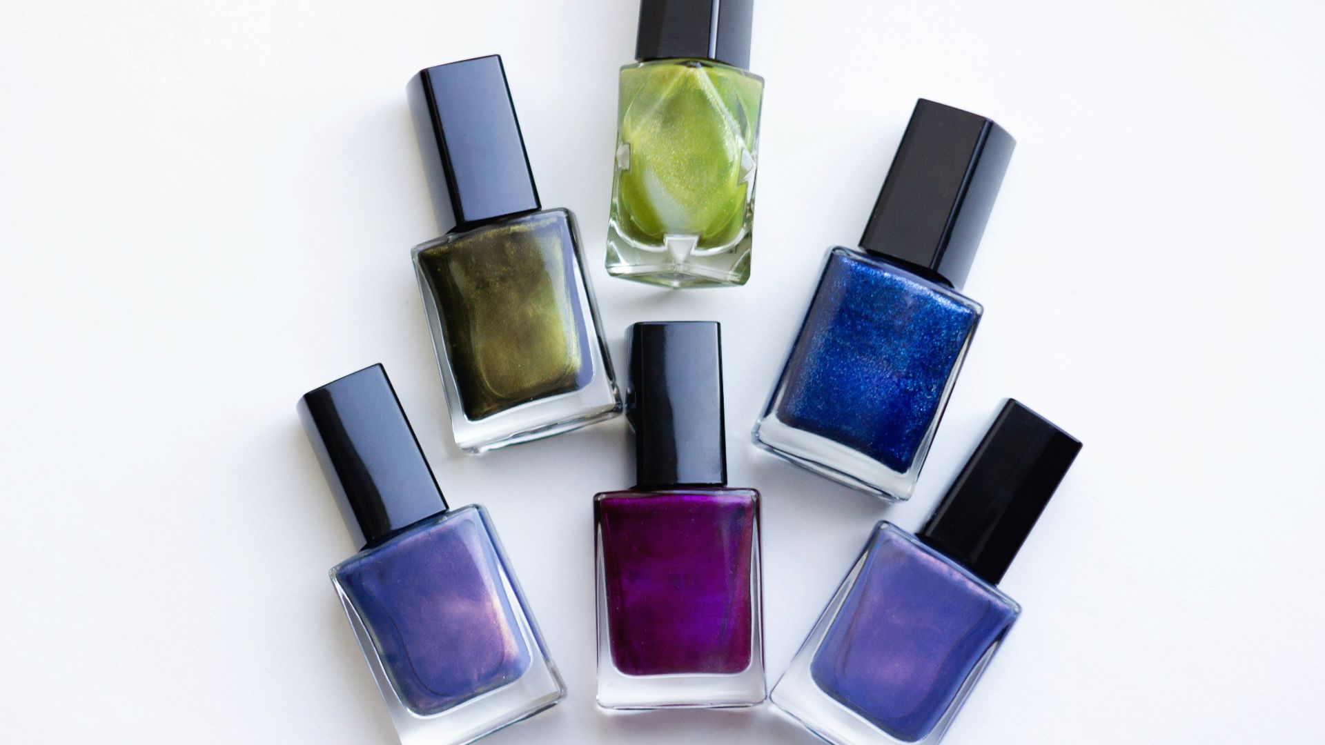 a group of five different colored nail polishes