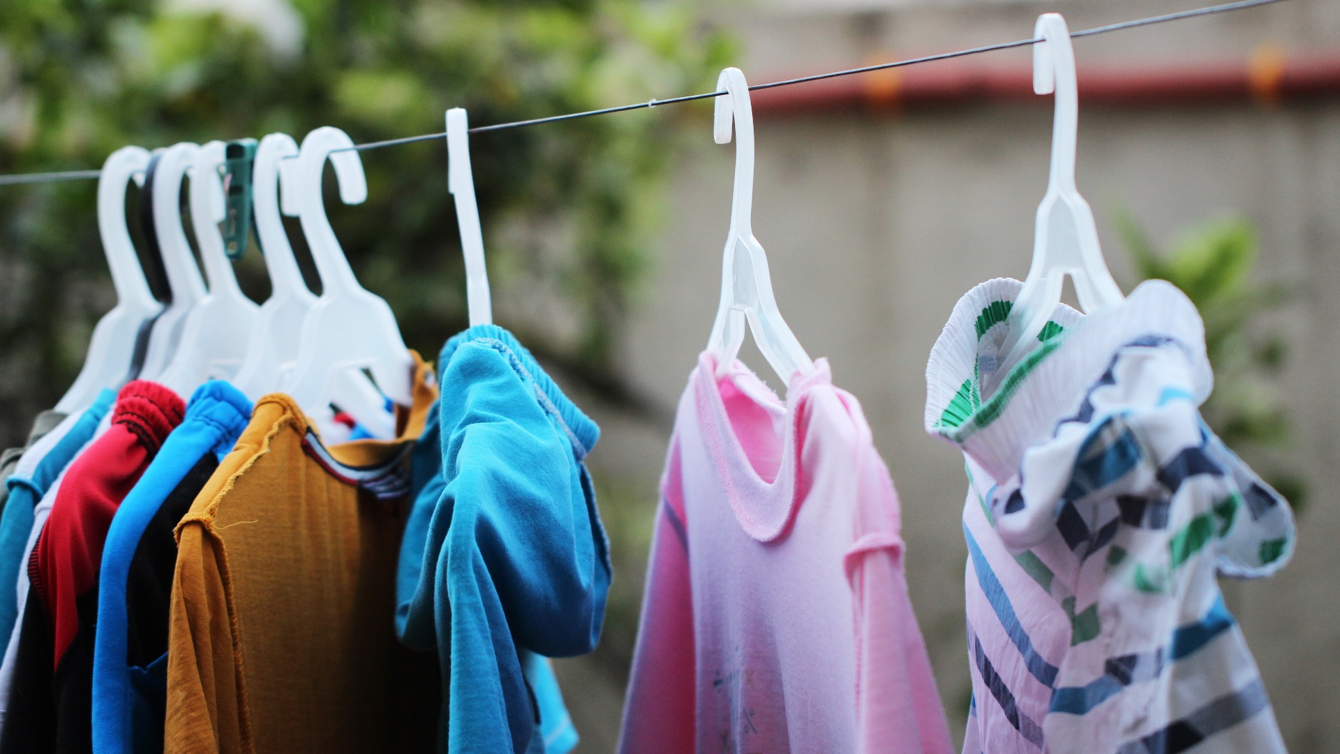 pink and blue clothes hanging on brown wooden cabinet