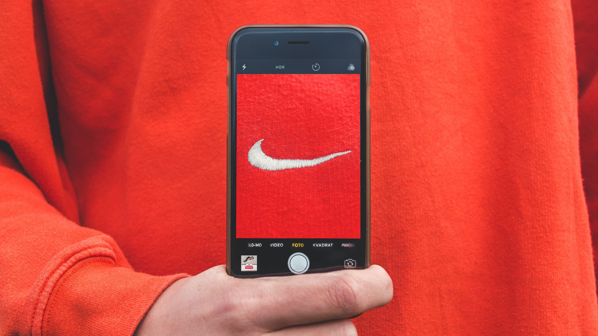 person holding iPhone taking picture on Nike label