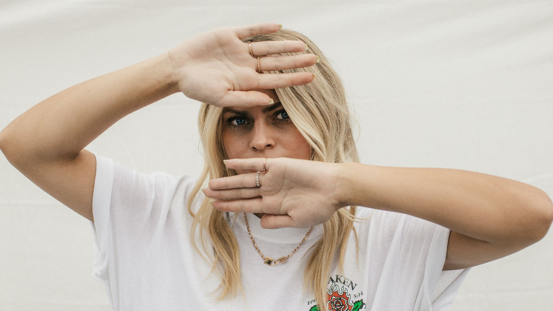 woman in white crew neck t-shirt covering her face with her hands