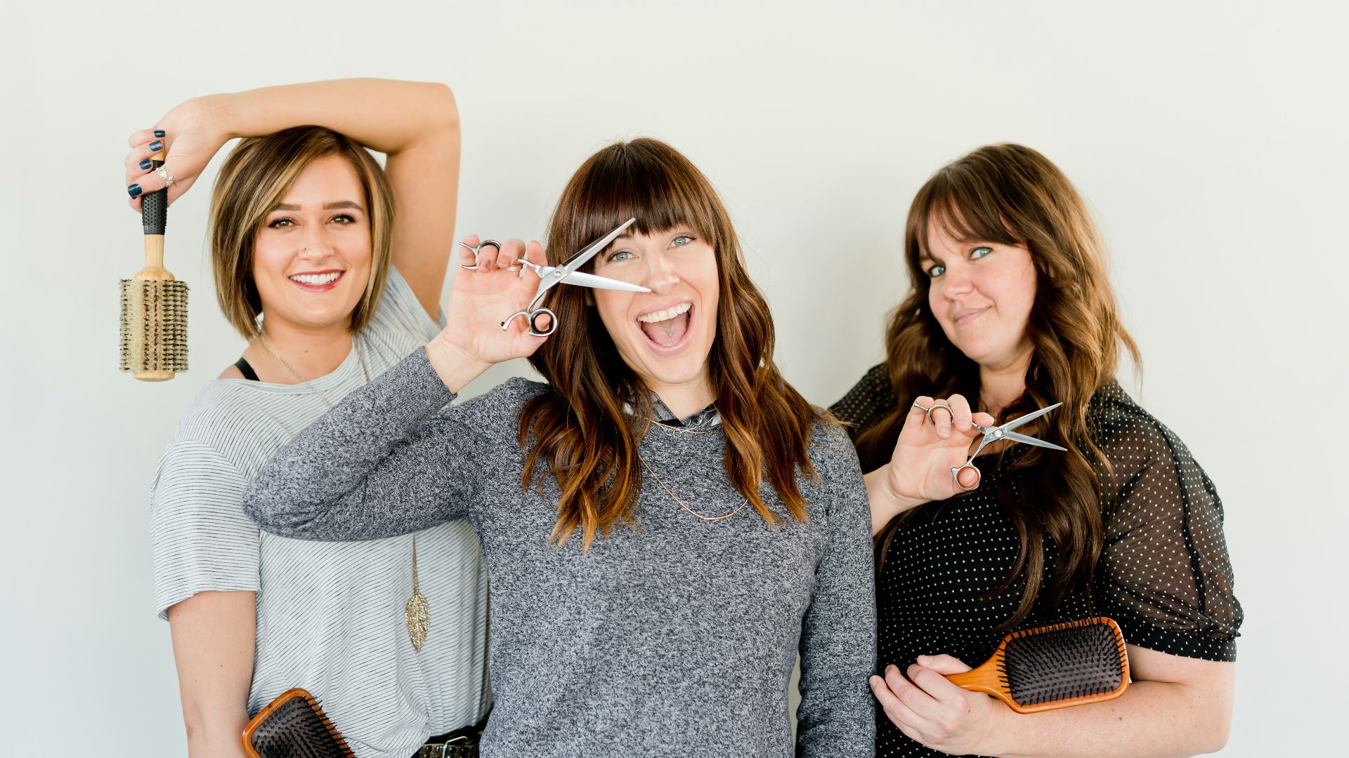 three women holding scissors and brush