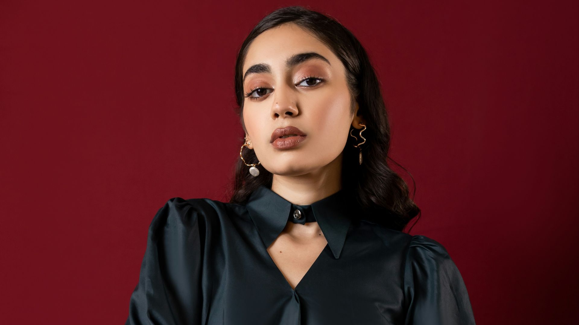 A woman in a dark teal blouse and black pants.