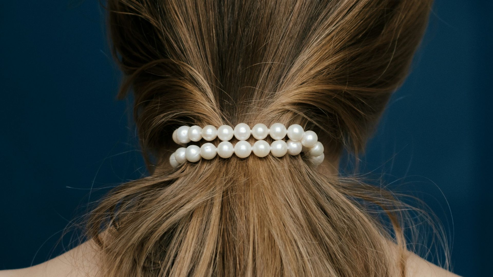 Woman's long brown hair tied with pearl bracelet